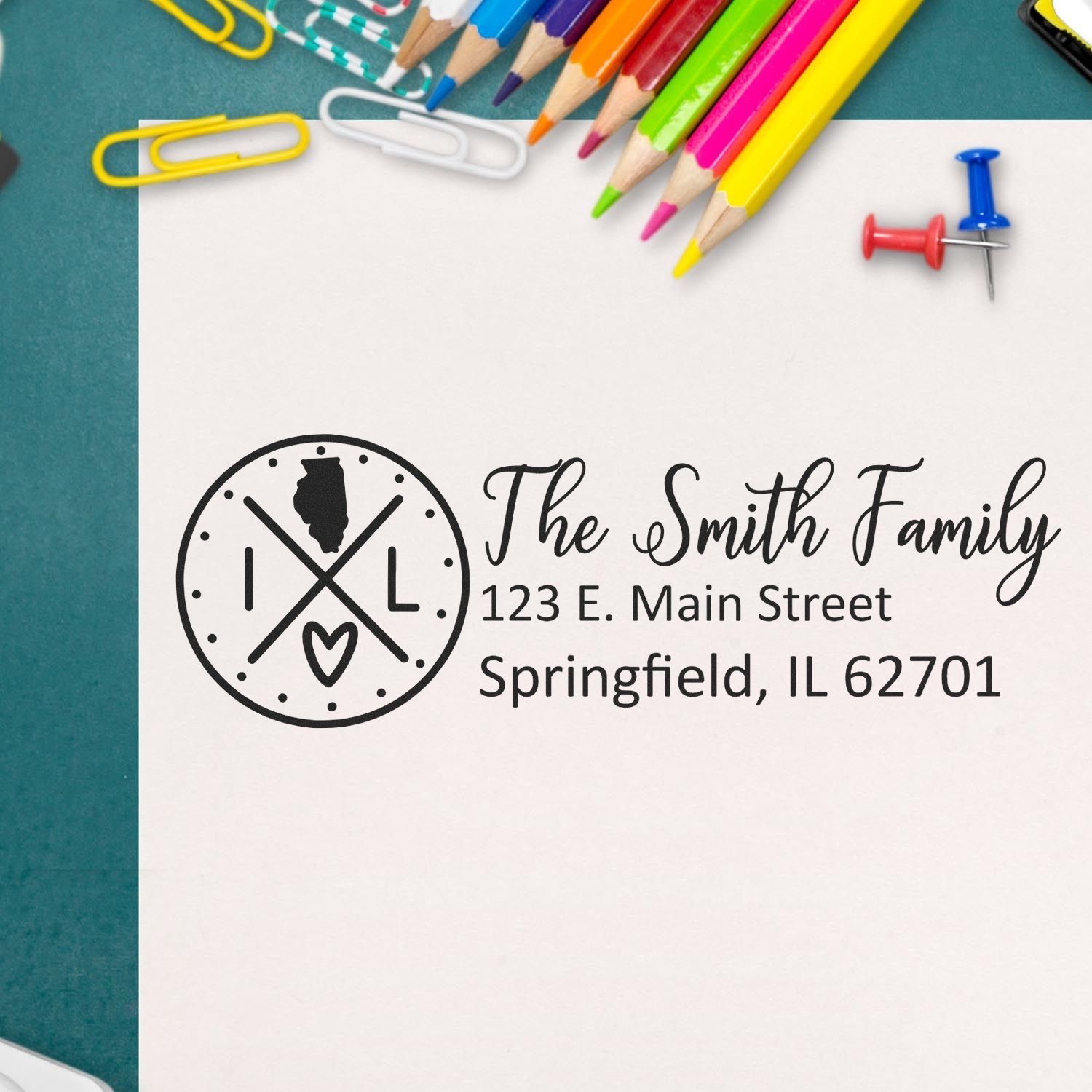 PSI Pre-Inked Illinois State Pride Customized Address Stamp on paper with colorful pencils and paperclips nearby, displaying a personalized address for The Smith Family in Springfield, IL.