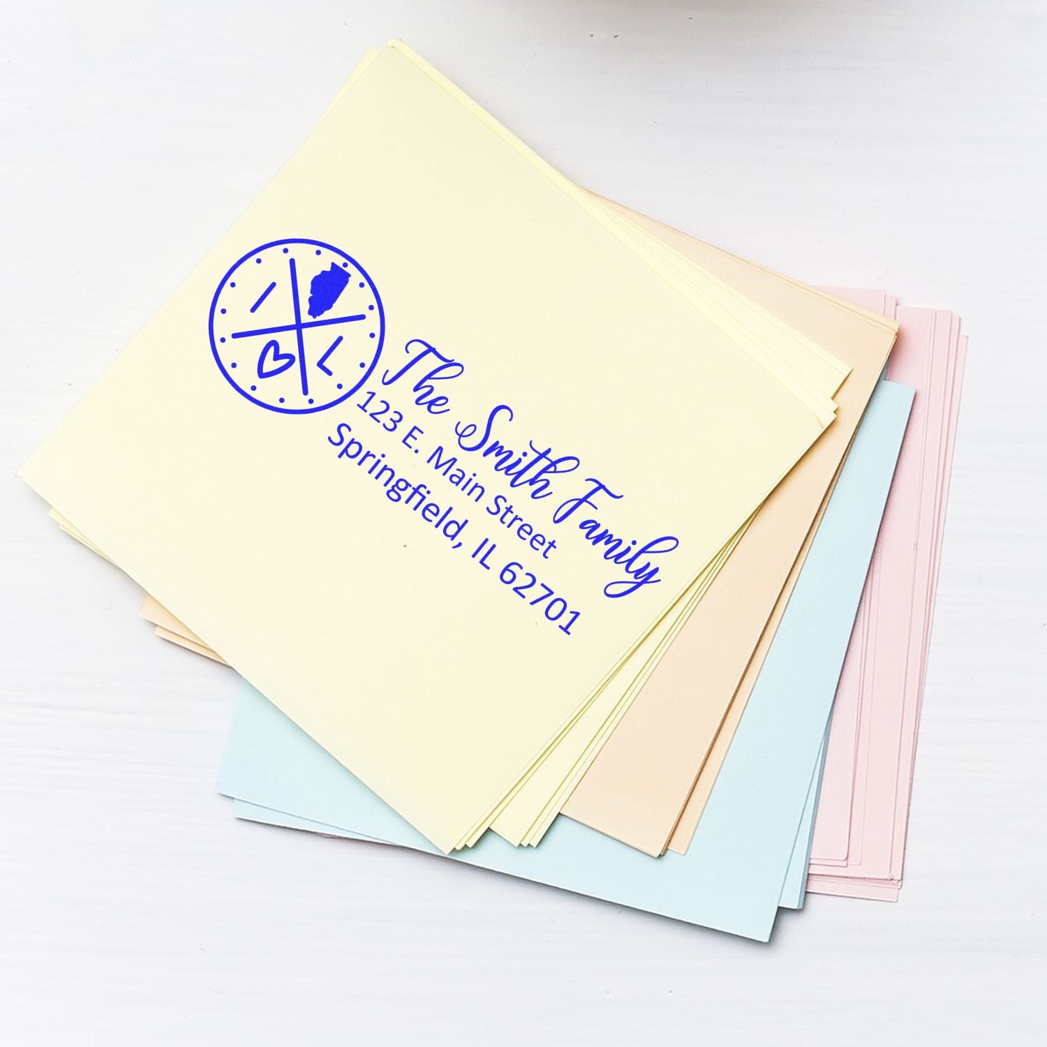 A stack of pastel envelopes featuring the Self-Inking State Love of Illinois Custom Address Stamp with a heart and state outline design, personalized with The Smith Family and Springfield address.