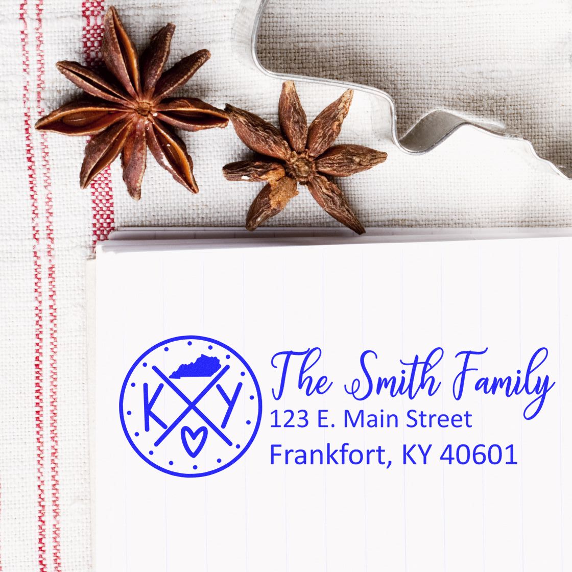 Kentucky State Pride Customized Address Stamp featuring The Smith Family on a notepad, with star anise and a cookie cutter on a textured cloth background.