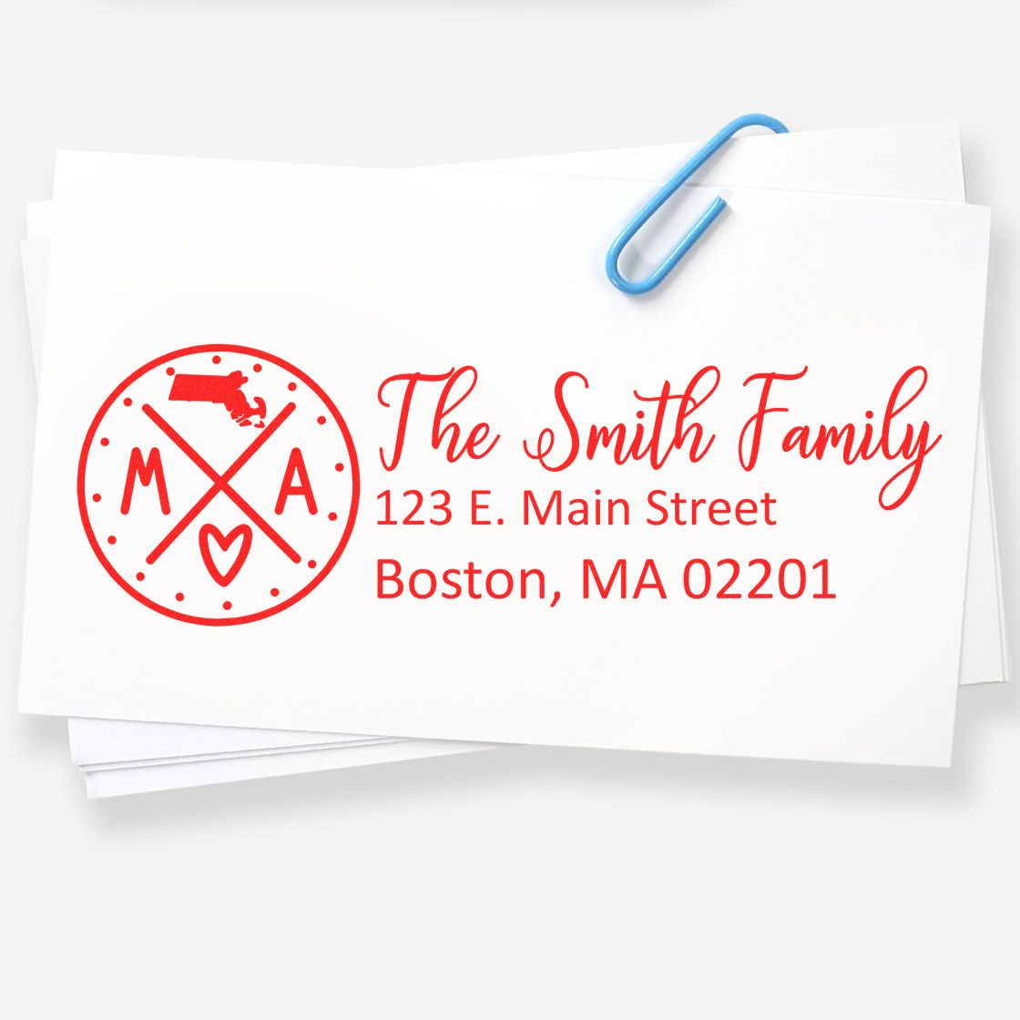 Slim Massachusetts Customized Pre-Inked Address Stamp on white paper, featuring red text and a circular design with a heart and state outline, clipped with a blue paperclip.