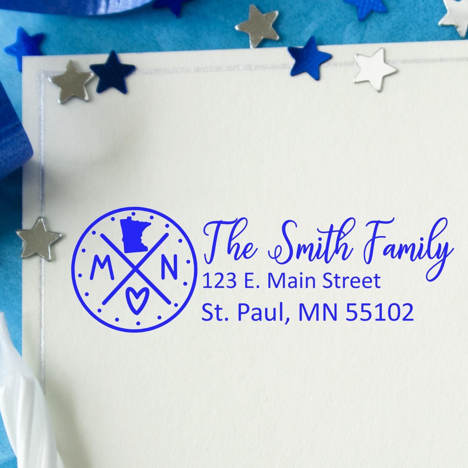 Slim Minnesota Customized Pre-Inked Address Stamp on an envelope with blue ink, featuring a Minnesota map and decorative stars.