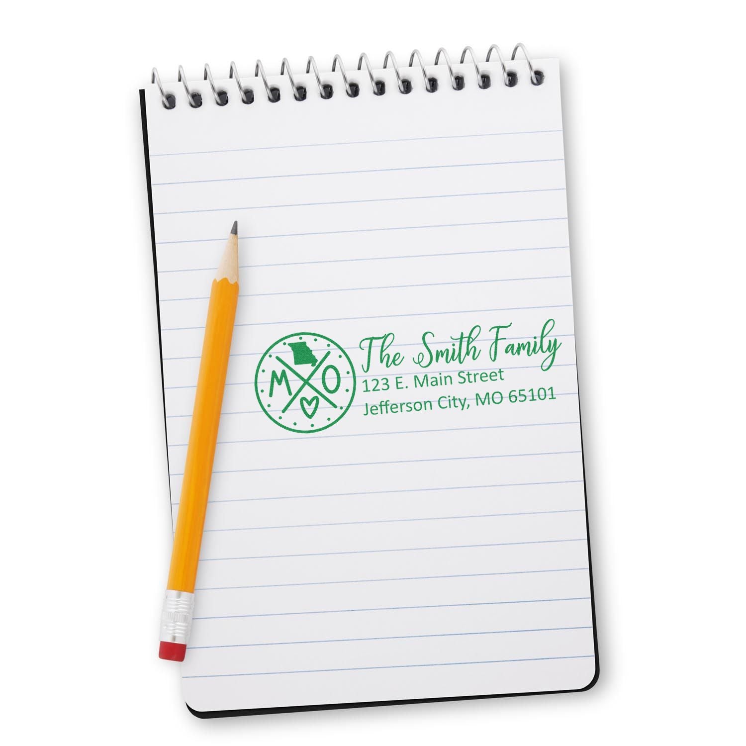 A notepad with a pencil displays a green imprint from the Self-Inking State Love of Missouri Custom Address Stamp, featuring a heart and state outline, personalized with a family name and address.