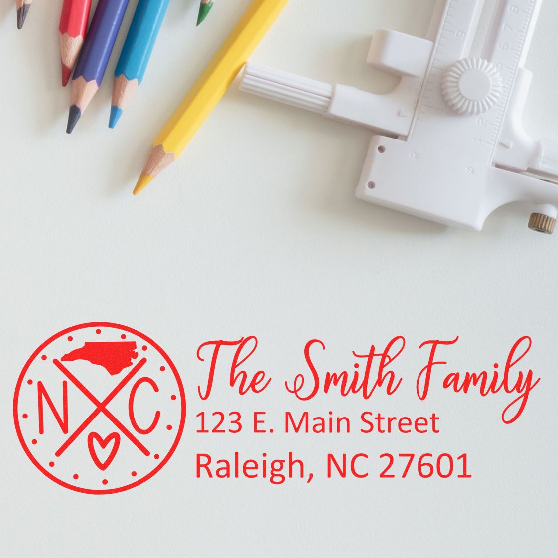 North Carolina State Pride Customized Address Stamp featuring The Smith Family with an NC logo, surrounded by colored pencils and a drafting tool on a light background.