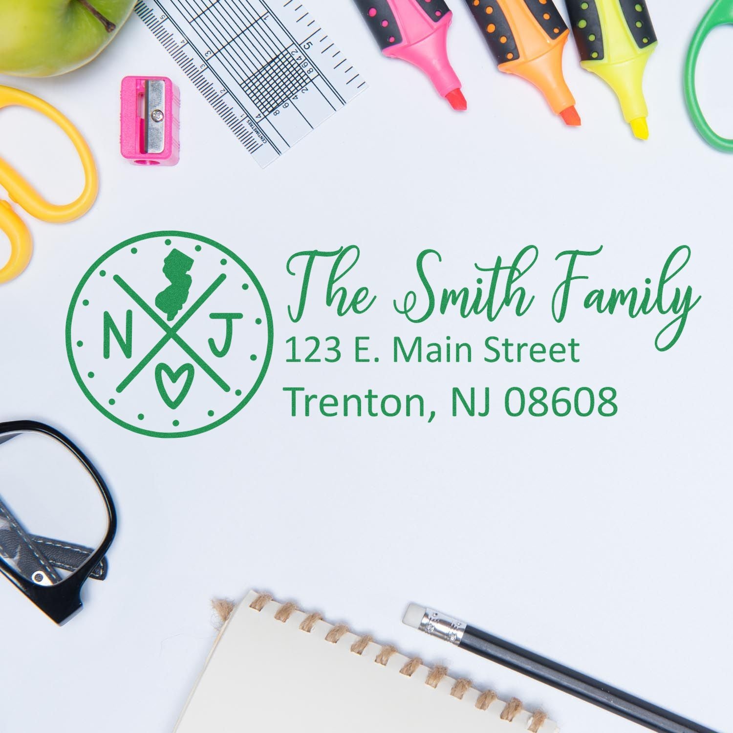 Desk with stationery items and a stamped envelope featuring the Self-Inking State Love of New Jersey Custom Address Stamp, displaying The Smith Family, 123 E. Main Street, Trenton, NJ 08608.