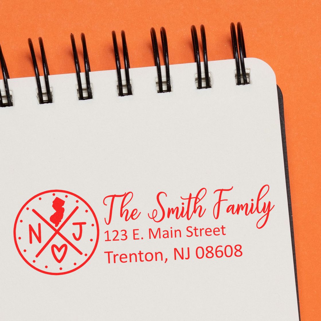 PSI Pre-Inked New Jersey State Pride Customized Address Stamp on a notebook, featuring a red NJ state design with The Smith Family and an address in Trenton, NJ.