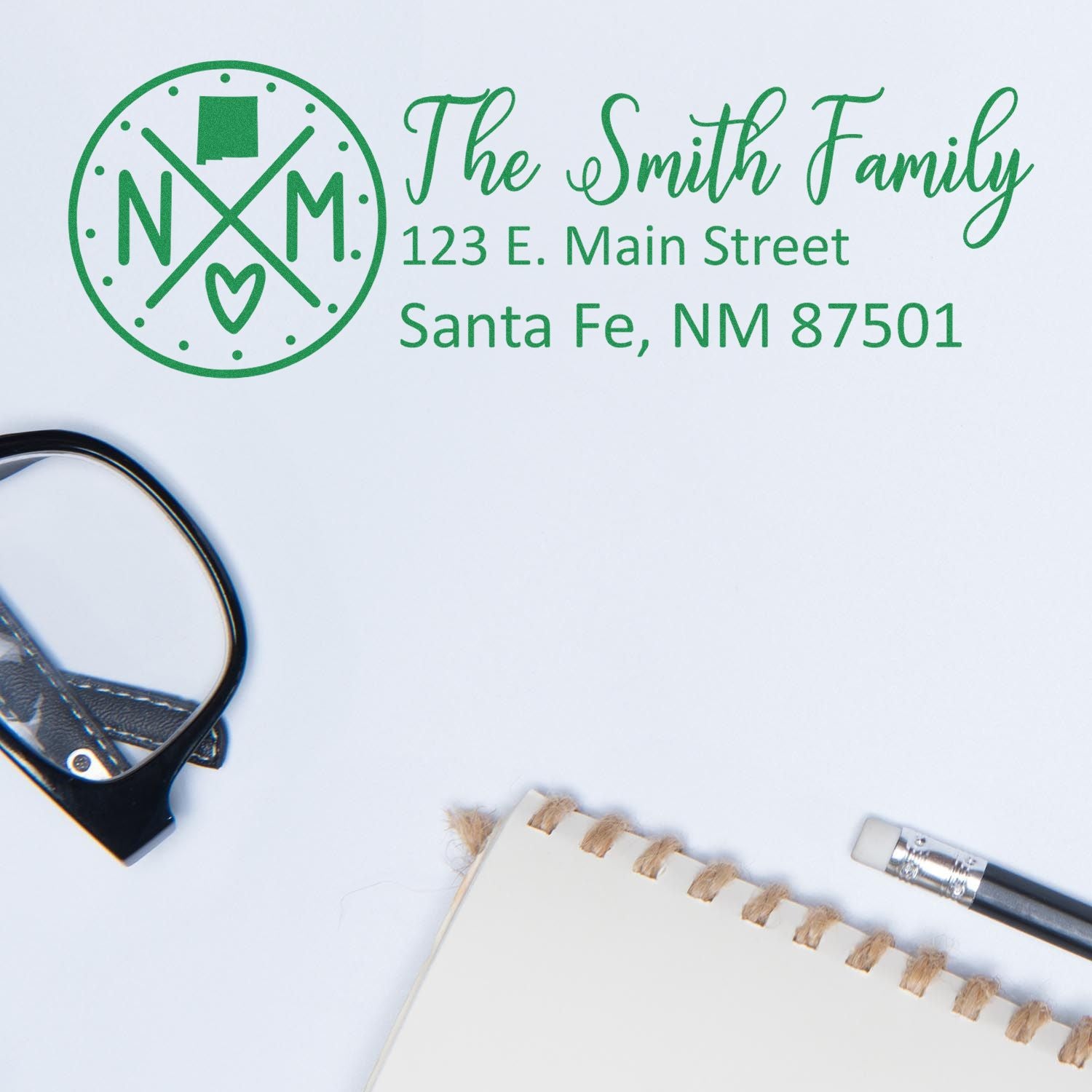 PSI Pre-Inked New Mexico State Pride Customized Address Stamp on paper with The Smith Family address, next to glasses and a pen on a notebook.