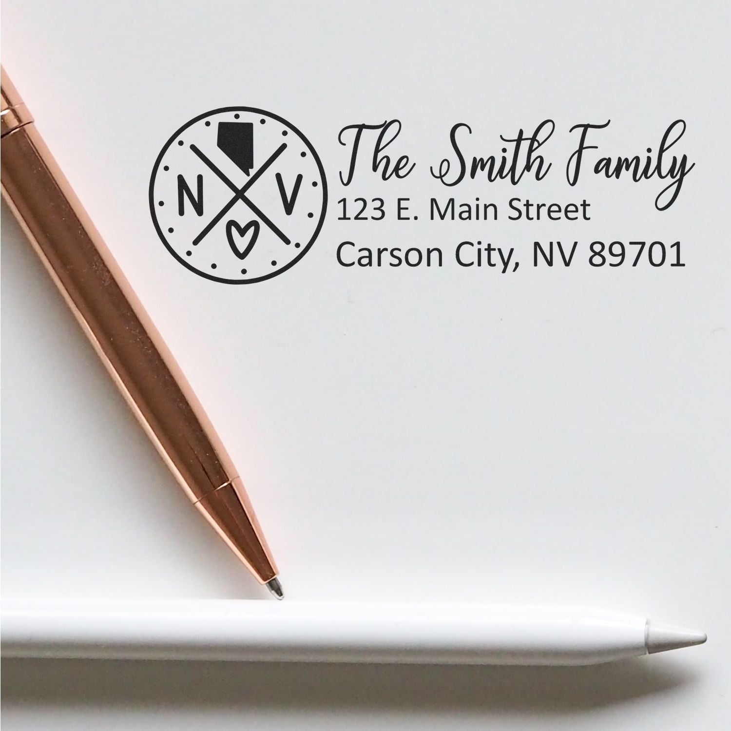 Nevada State Pride Customized Address Stamp featuring The Smith Family with a Nevada emblem, next to a rose gold pen and white pencil on a light surface.