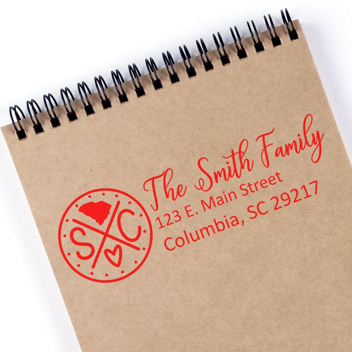 Slim South Carolina Customized Pre-Inked Address Stamp imprint on a brown spiral notebook, featuring a red design with 'The Smith Family' and address in Columbia, SC.