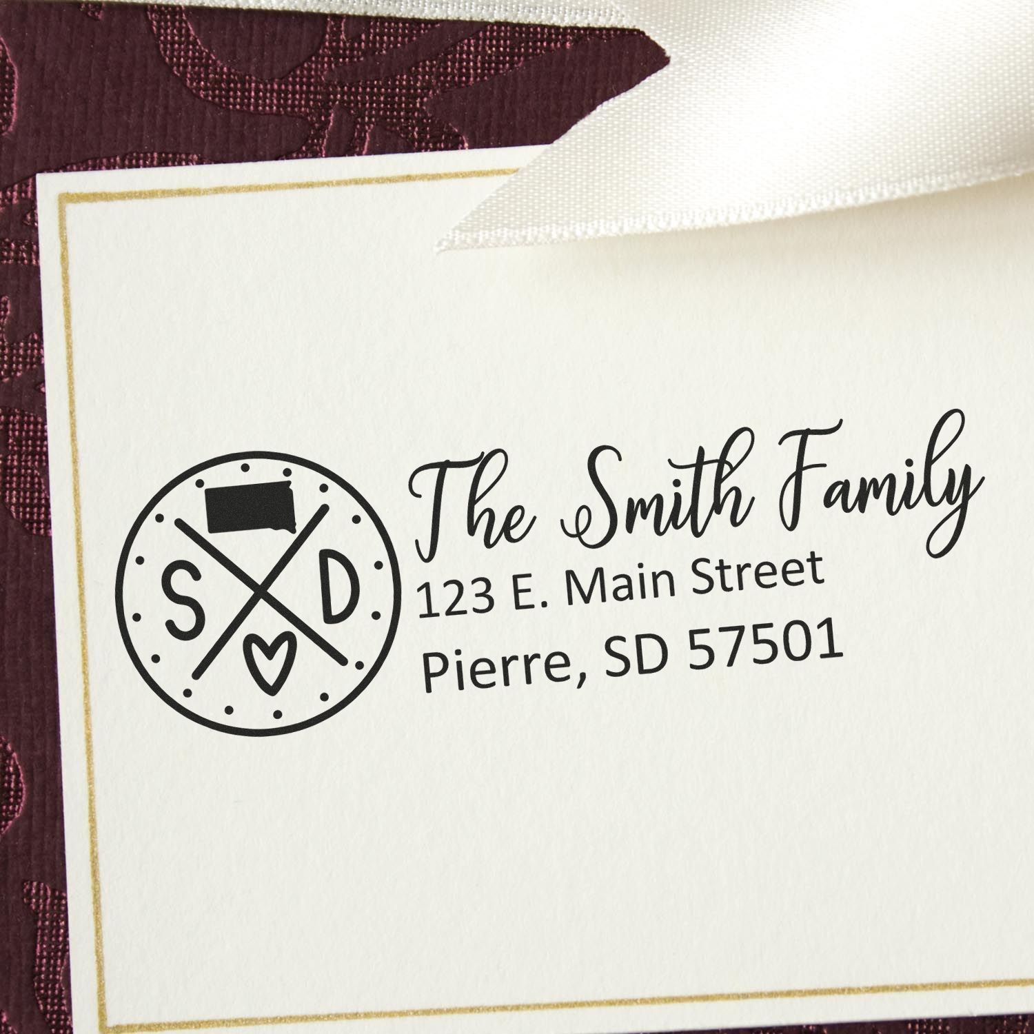 Self-Inking State Love of South Dakota Custom Address Stamp on a card with The Smith Family, 123 E. Main Street, Pierre, SD 57501 in elegant script, featuring a South Dakota emblem.