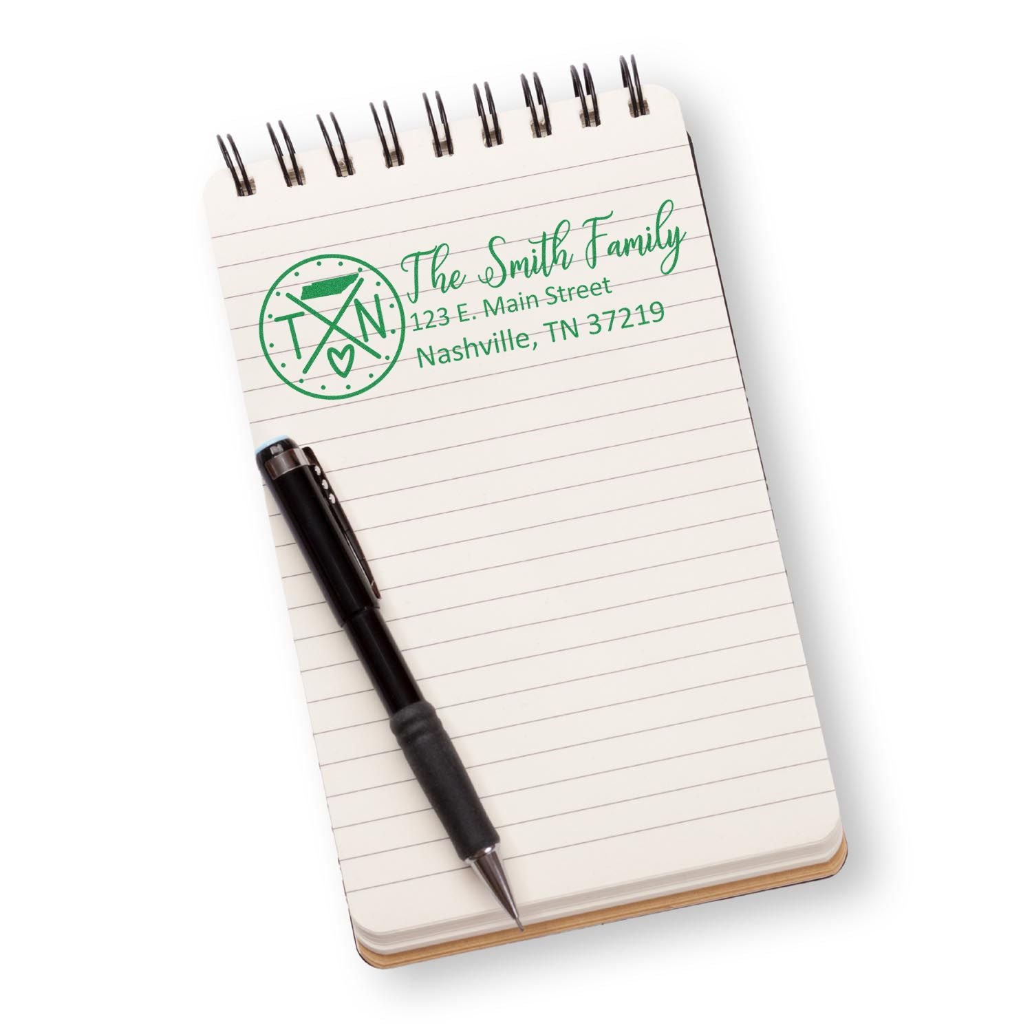 PSI Pre-Inked Tennessee State Pride Customized Address Stamp on a notepad, featuring a green design with The Smith Family and an address in Nashville, TN. A black pen rests beside it.