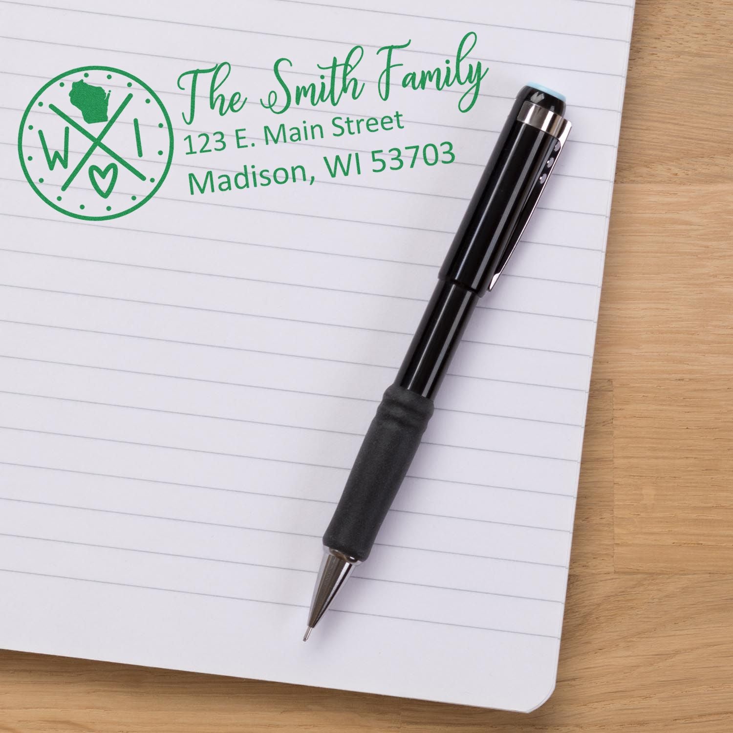 A PSI Pre-Inked Wisconsin State Pride Customized Address Stamp on a notepad, featuring a green design with a pen beside it.