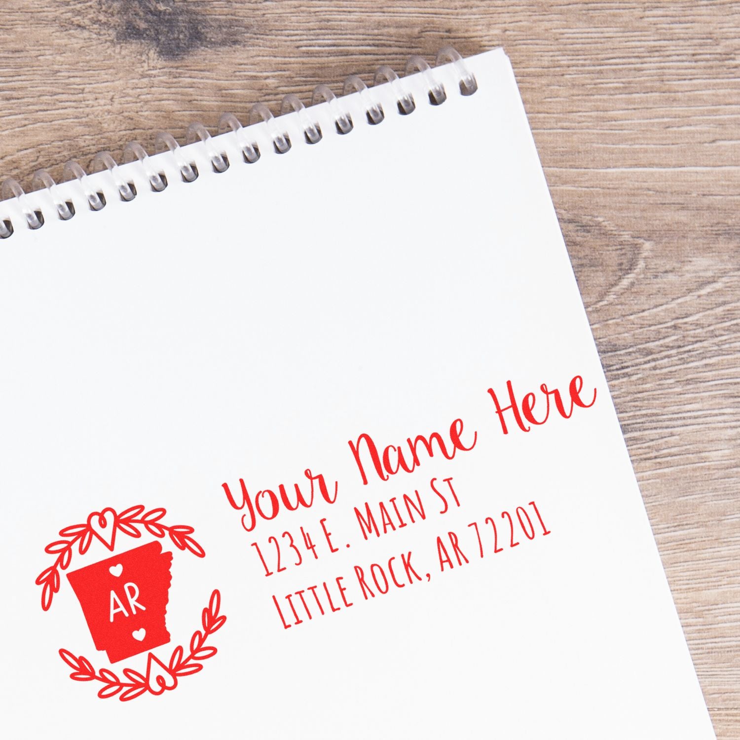 Arkansas State Custom Return Address Stamp on a notepad, featuring a red state outline with AR and decorative elements, displaying a sample address in elegant red script.