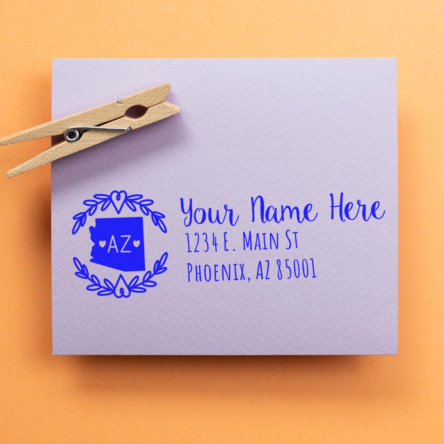 PSI Pre-Inked Arizona State Customized Address Stamp on a lavender envelope with a wooden clothespin, featuring a blue Arizona state design and sample address text.