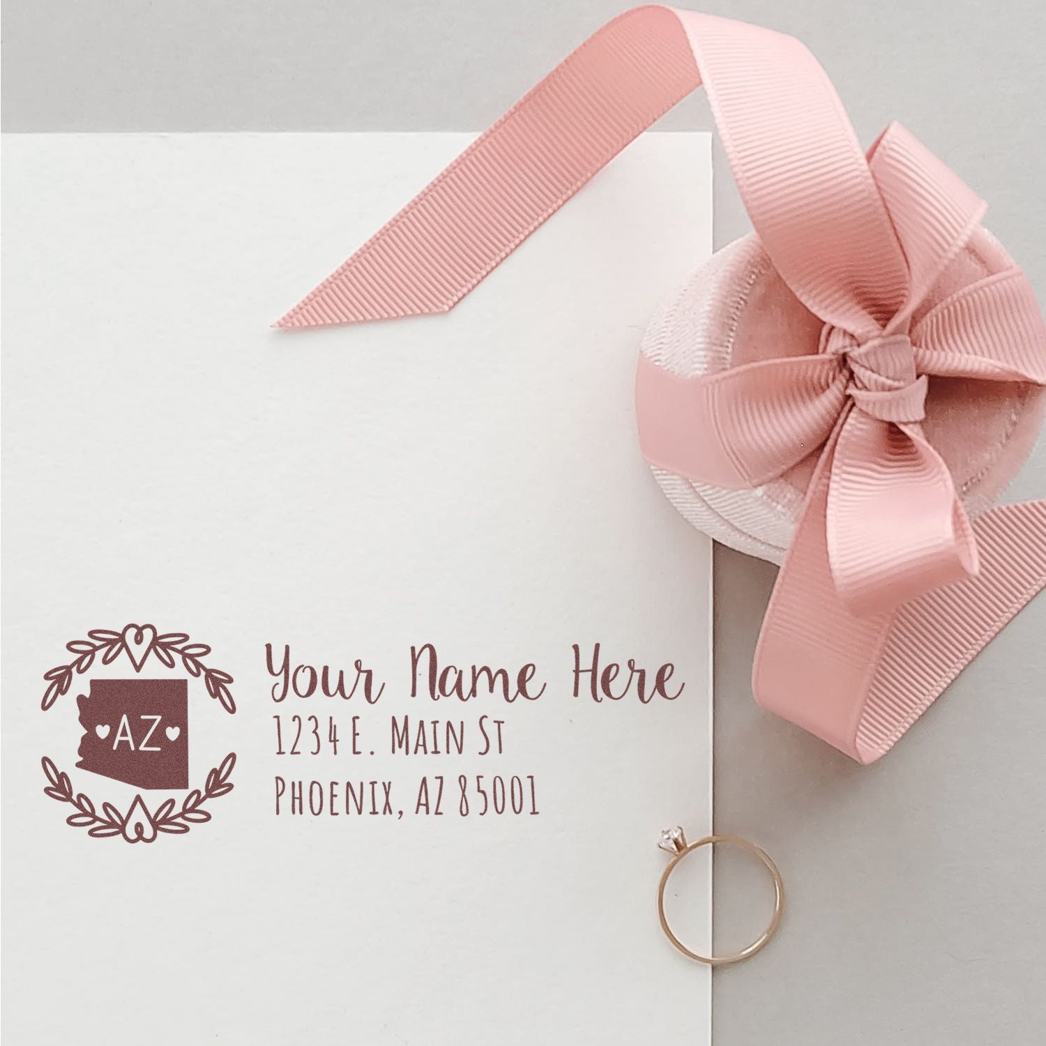 PSI Pre-Inked Arizona State Customized Address Stamp on an envelope with a pink ribbon and ring, showcasing elegant design and personalized address details.