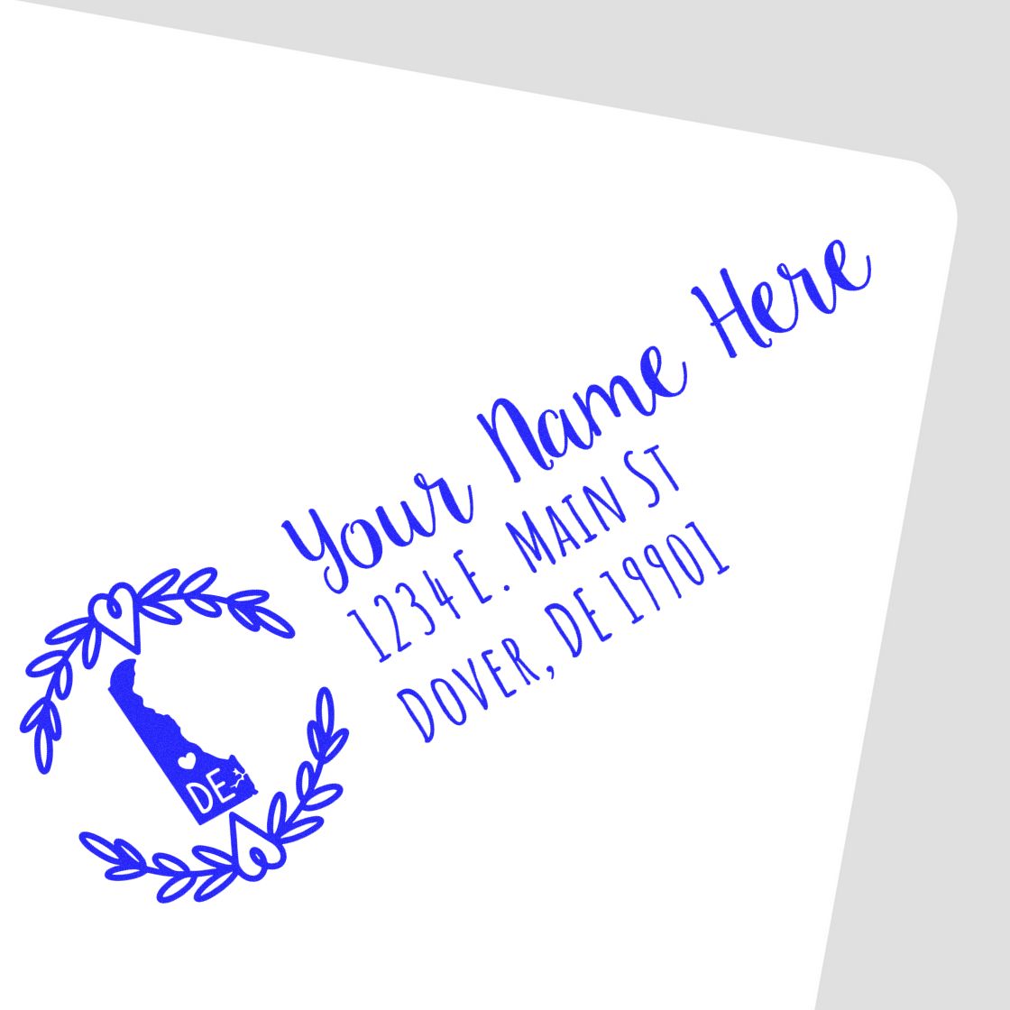 Delaware State Custom Return Address Stamp featuring a blue design with a state outline and heart accents, personalized with Your Name Here and an address in Dover, DE, on a white envelope.