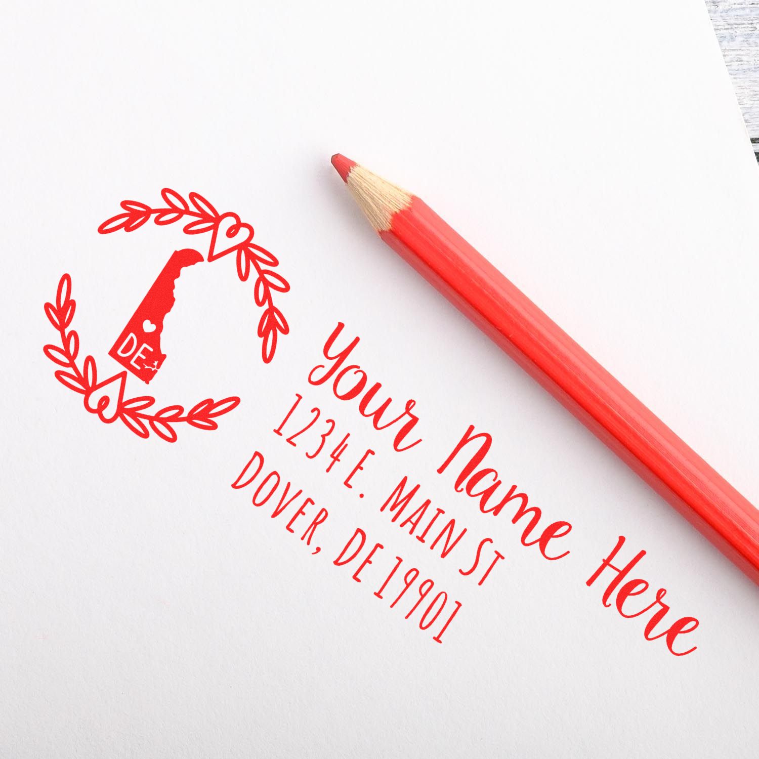 Image of a PSI Pre-Inked Delaware State Customized Address Stamp imprint on paper, featuring a red Delaware outline with a heart design, next to a red pencil.