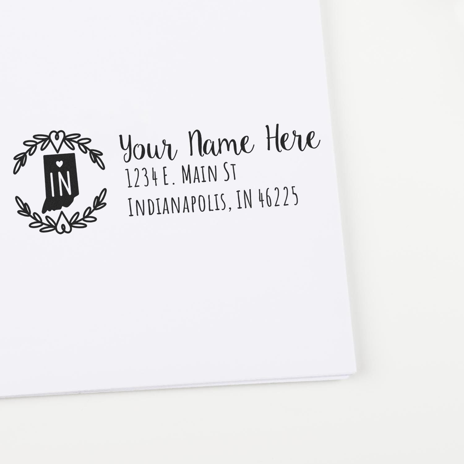 Indiana State Custom Return Address Stamp on white paper, featuring a decorative 'IN' emblem with floral accents and sample address text in elegant script.