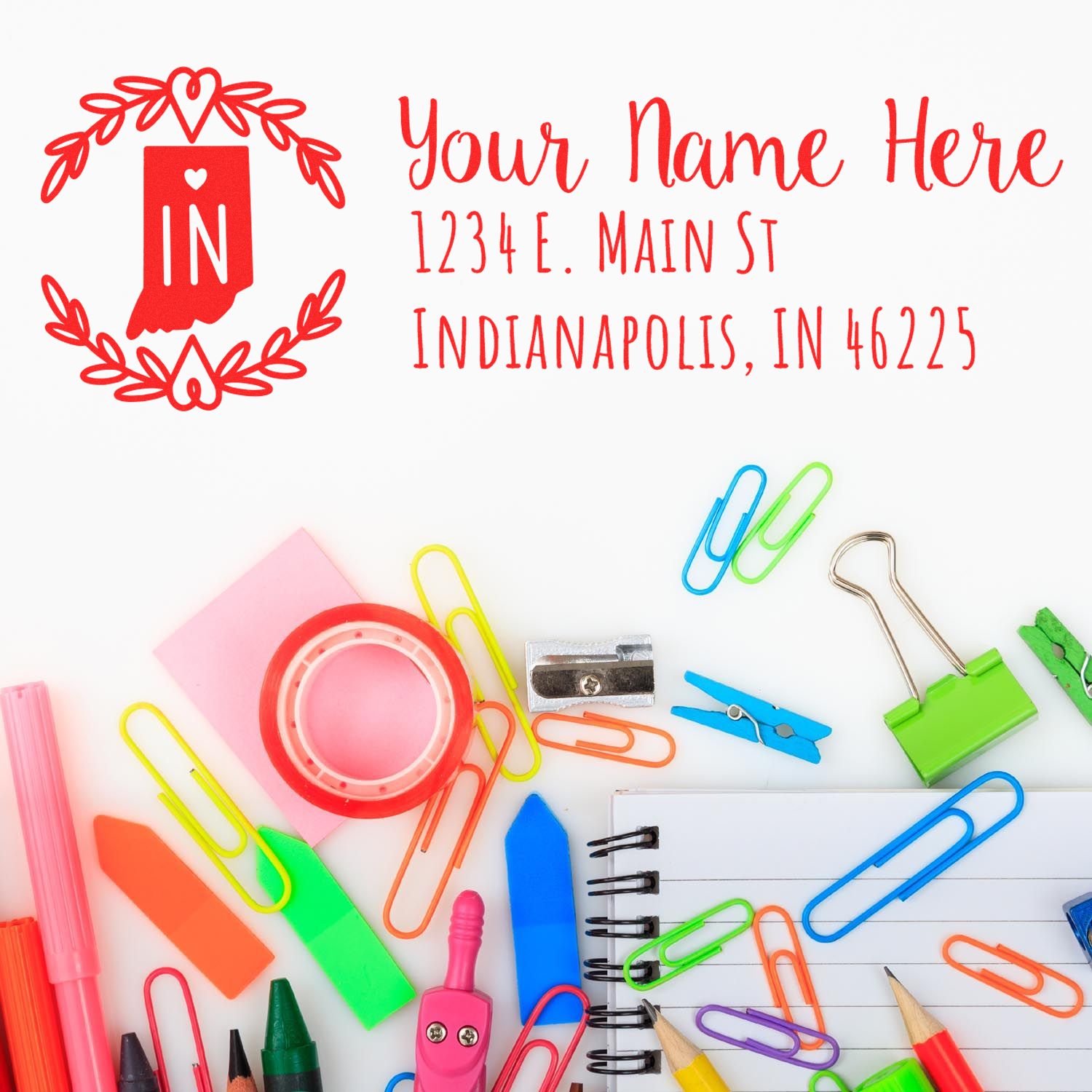 Indiana State Custom Return Address Stamp displayed on a white surface with colorful office supplies, including paper clips, pens, and a notebook. The stamp features a red Indiana state outline with text.