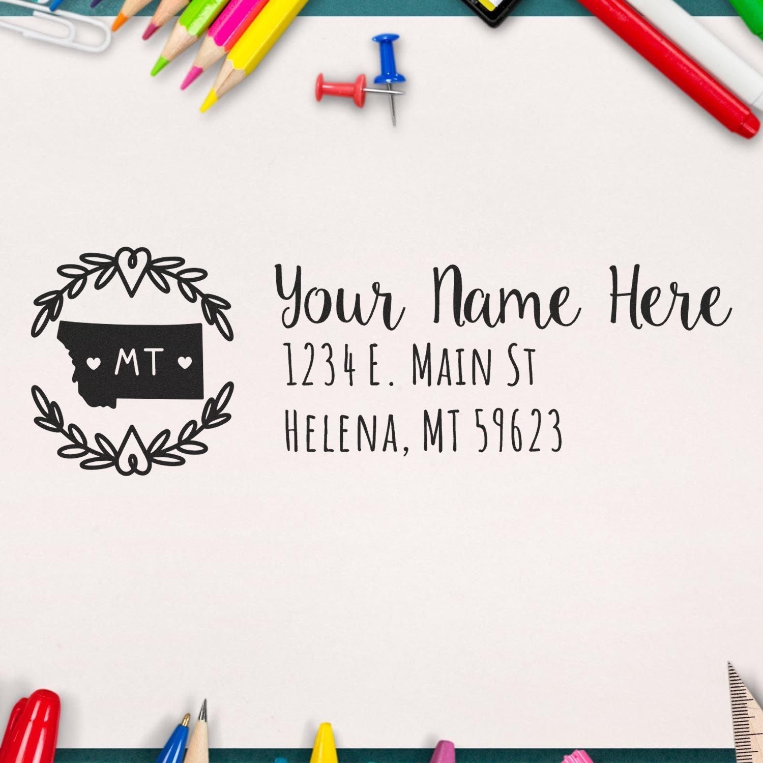 Self-Inking State Wreath of Montana Address Stamp on paper with colorful stationery. Features Montana state outline and customizable address in elegant font. Perfect for personalizing mail.