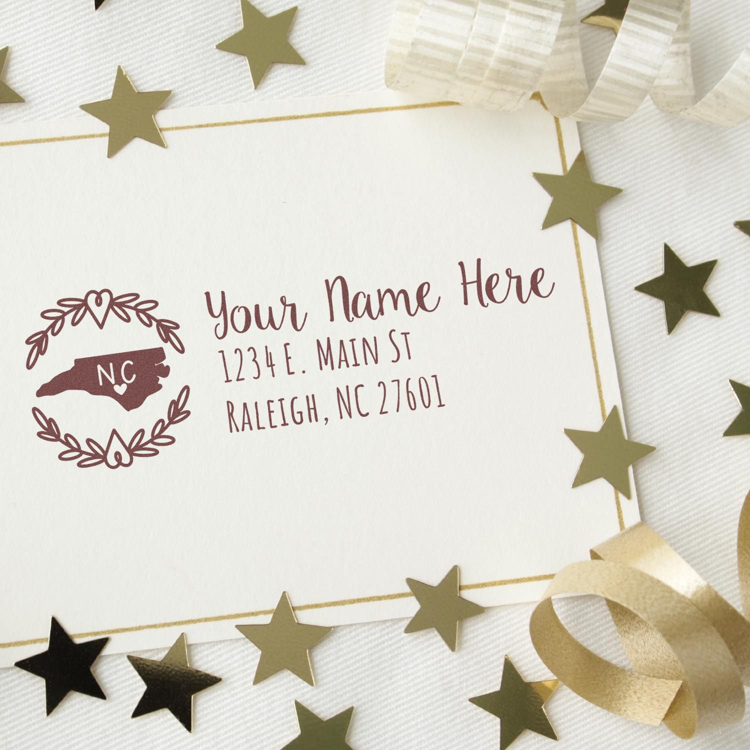 Self-Inking State Wreath of North Carolina Address Stamp on a card with gold stars and ribbon, featuring a customizable address and state design. Perfect for personalizing mail with style.