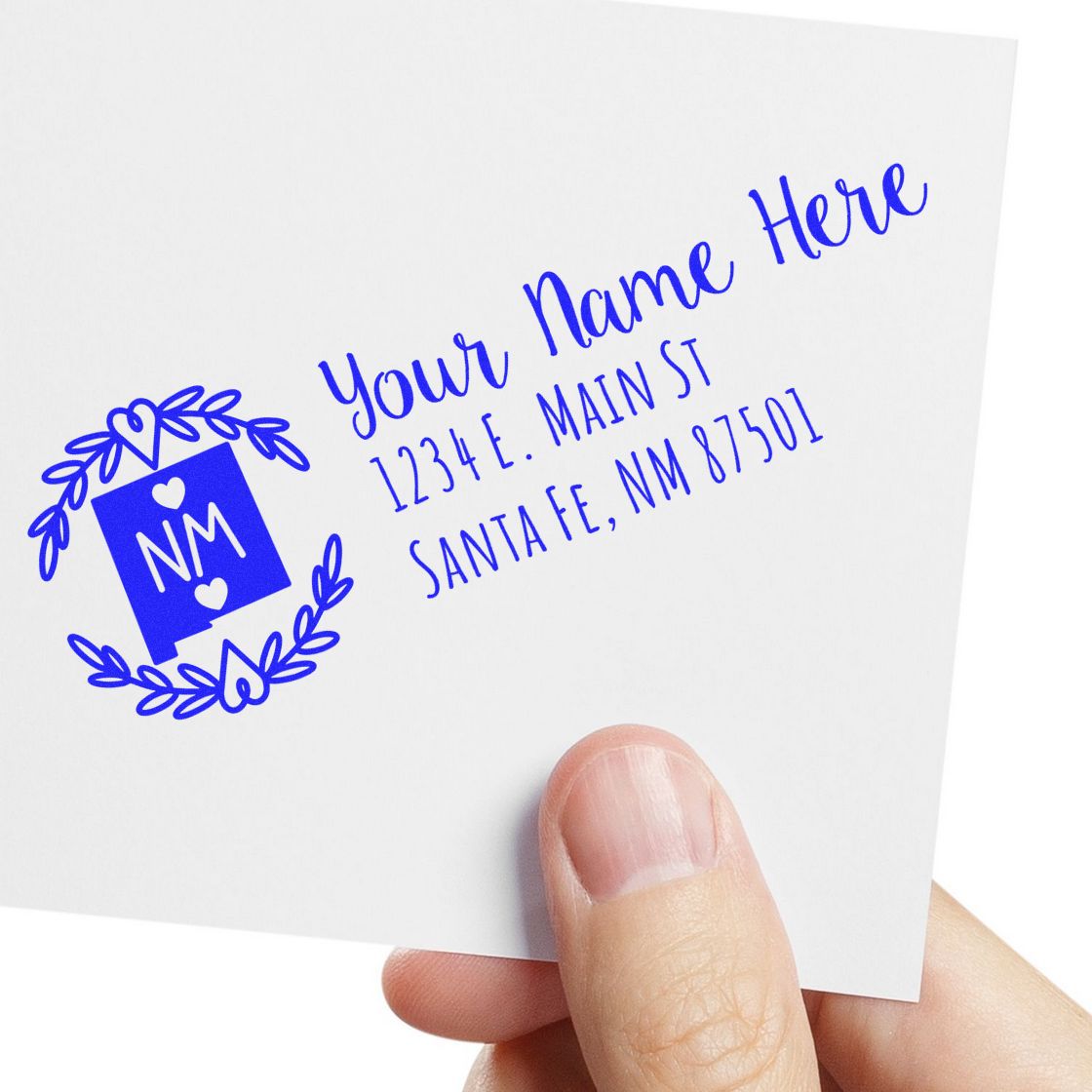 A hand holds an envelope stamped with the PSI Pre-Inked New Mexico State Customized Address Stamp, featuring a blue design with NM and sample address text in elegant font.