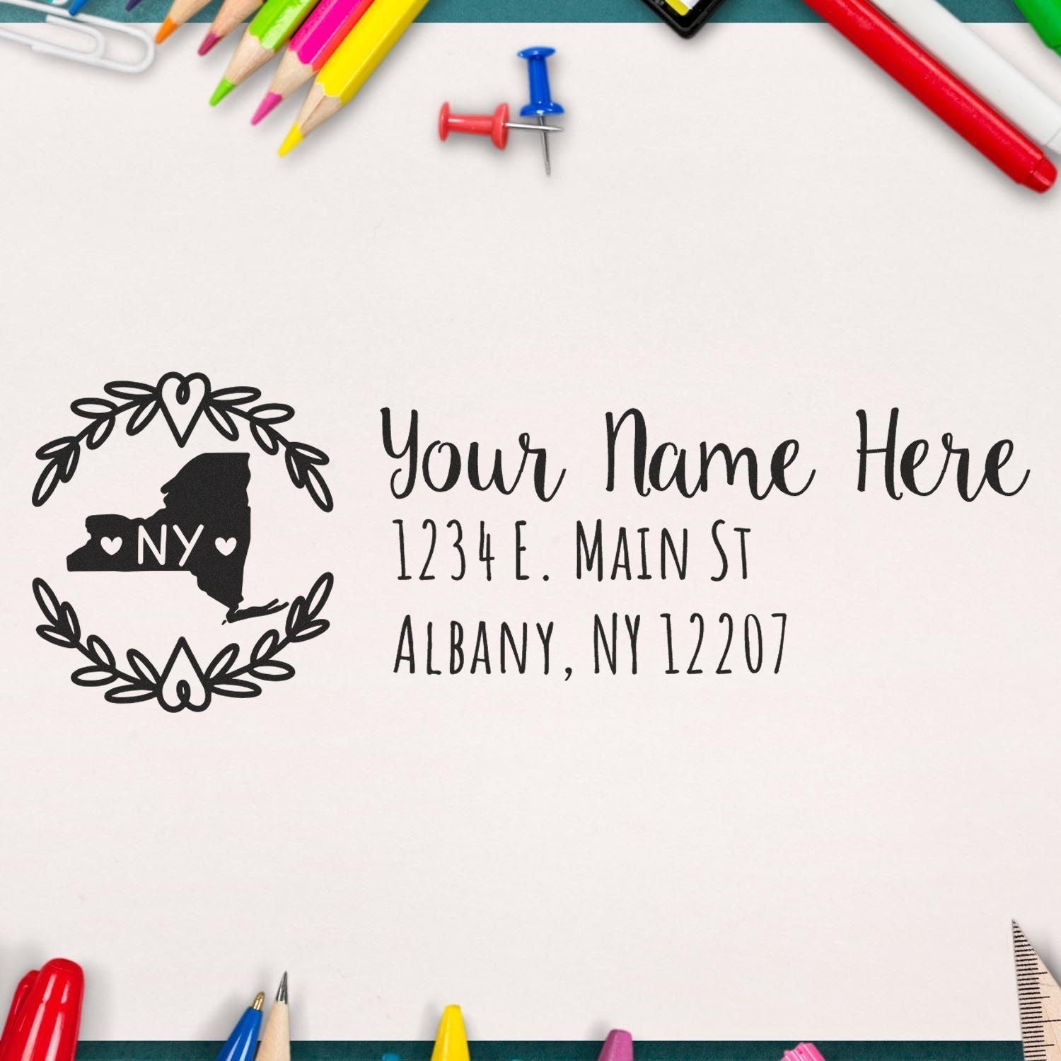 PSI Pre-Inked New York State Customized Address Stamp on paper, surrounded by colorful stationery, featuring a heart-accented NY state outline and sample address text.