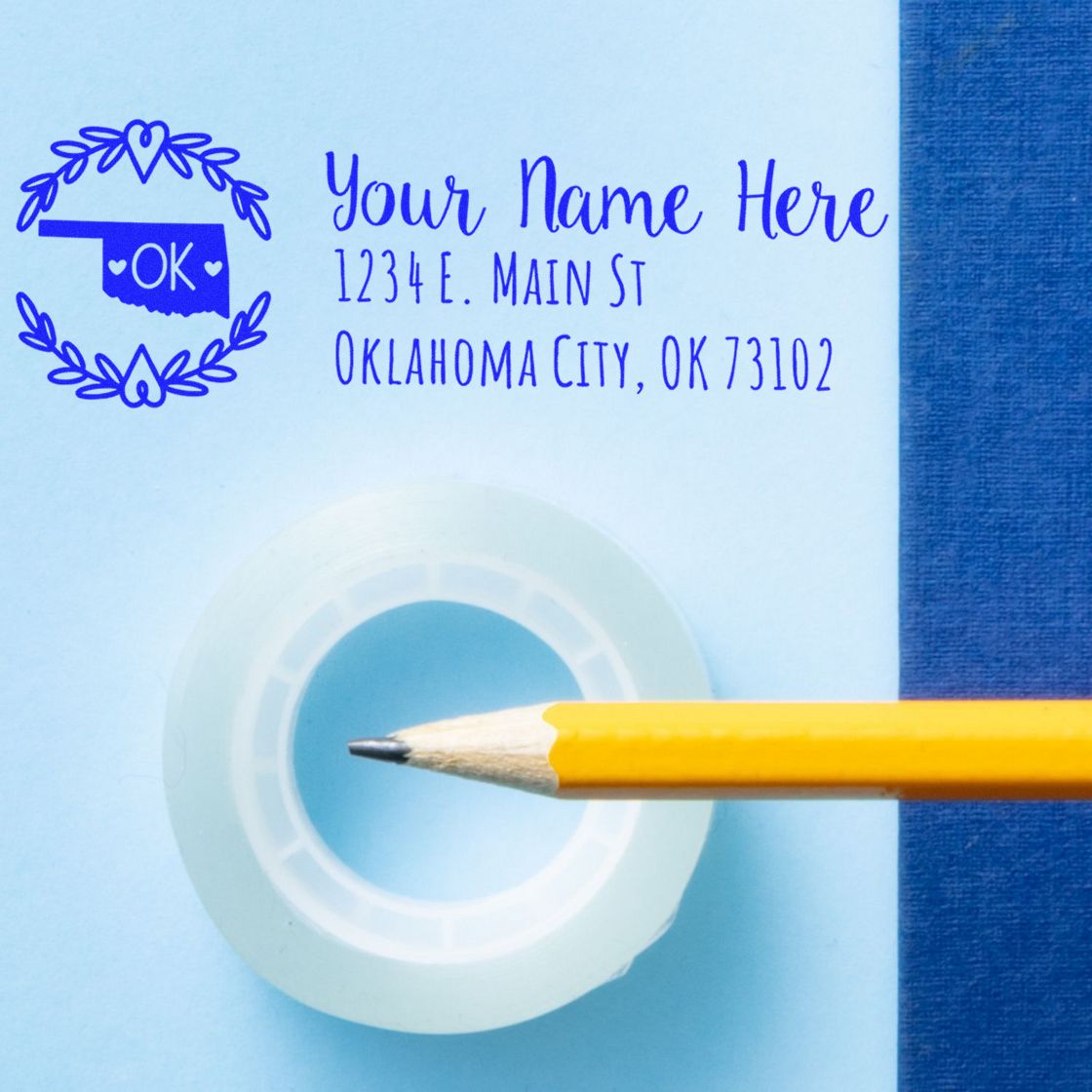 Oklahoma State Custom Return Address Stamp on blue paper with a pencil and tape. Features a decorative state outline and personalized address in blue ink.