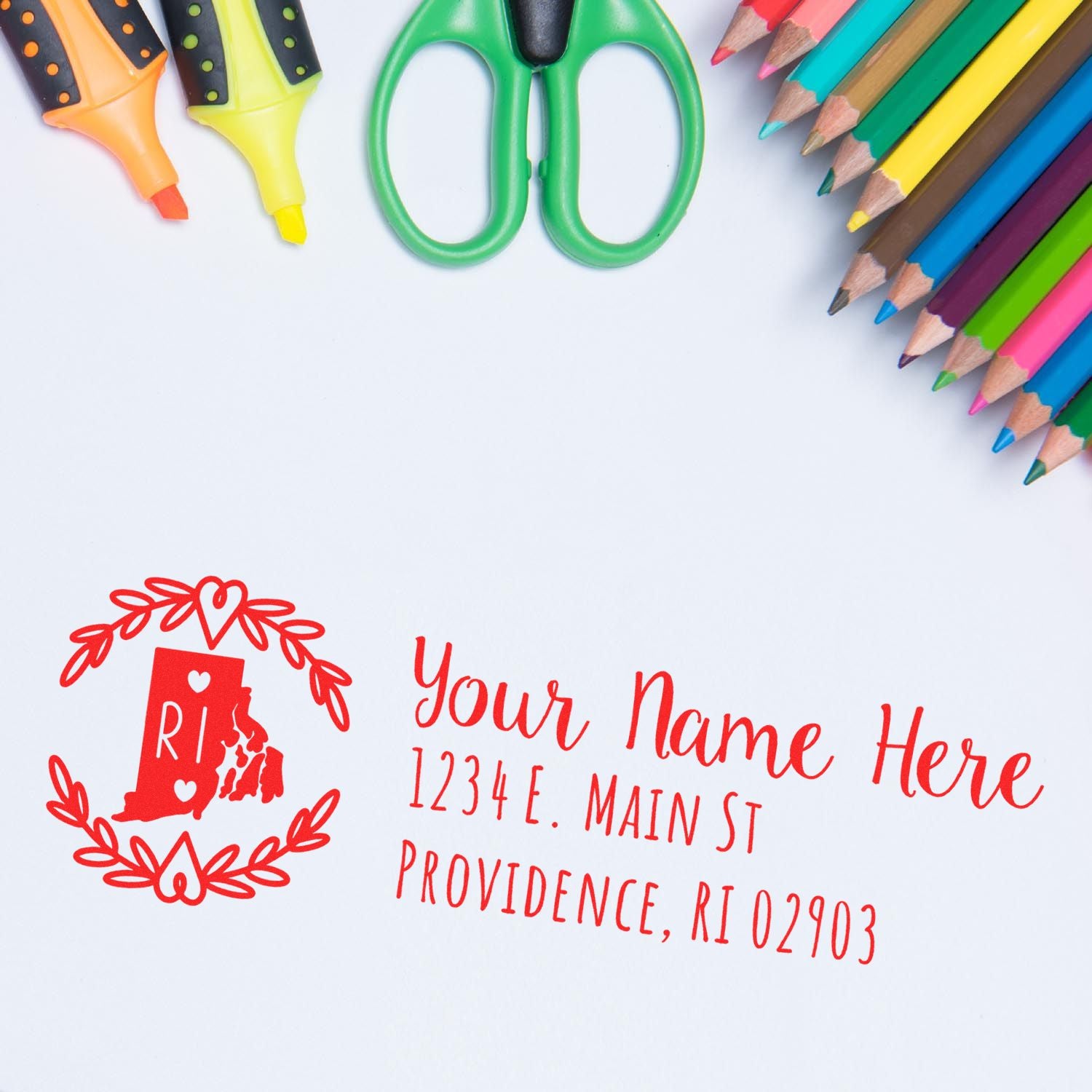 PSI Pre-Inked Rhode Island State Customized Address Stamp in red ink on white paper, surrounded by colorful pencils and scissors, featuring a map outline and decorative border.