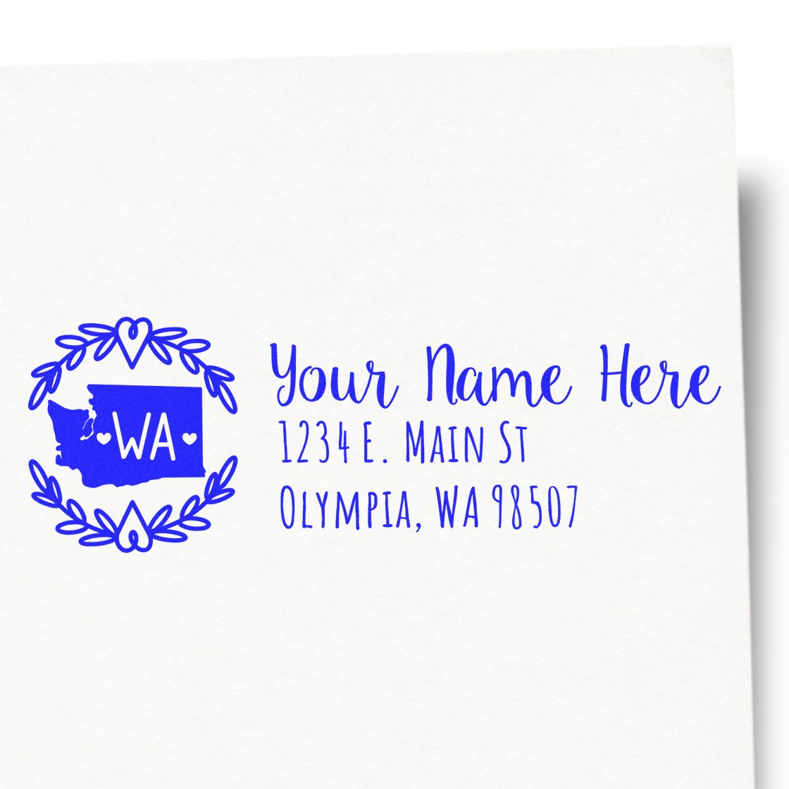 Self-Inking State Wreath of Washington Address Stamp on white paper, featuring a blue Washington state outline with a wreath and customizable address text.