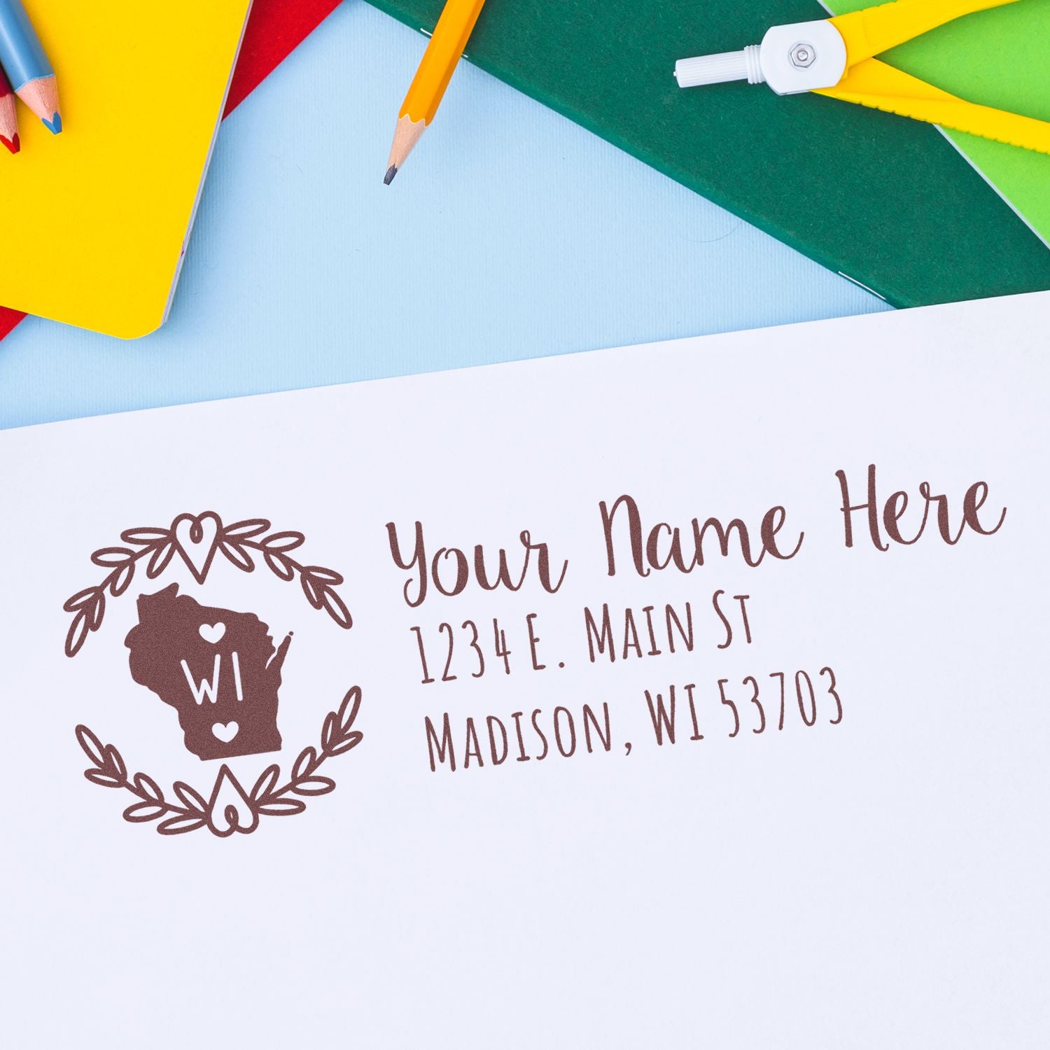 Wisconsin State Custom Return Address Stamp on white paper, featuring a decorative outline of Wisconsin with WI inside, surrounded by a wreath, and sample address text in elegant font.