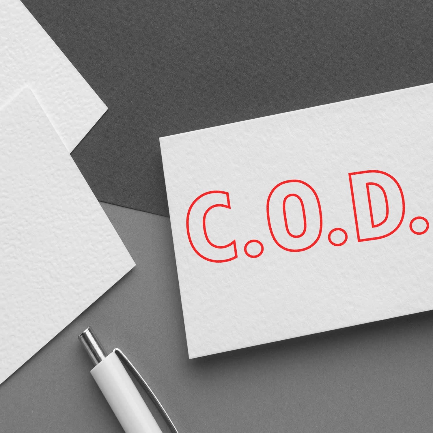 Large Pre-Inked C.O.D. Outline Stamp in red ink on white paper, with a pen and additional paper sheets on a gray background.