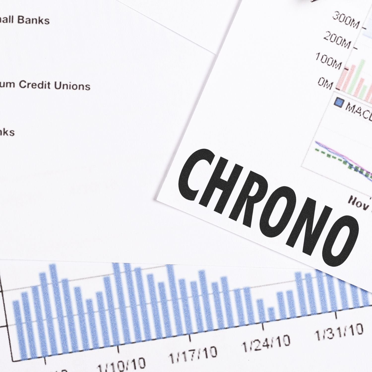 Large Pre-Inked Chrono Stamp on a desk with financial charts and graphs in the background.