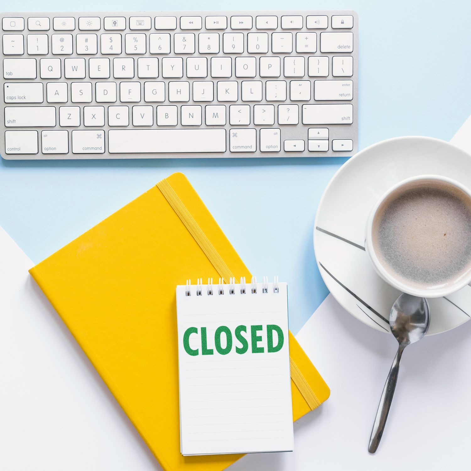 Yellow notebook, keyboard, coffee cup, and Large Pre-Inked Closed Stamp on a notepad with CLOSED text on a light blue and white background.