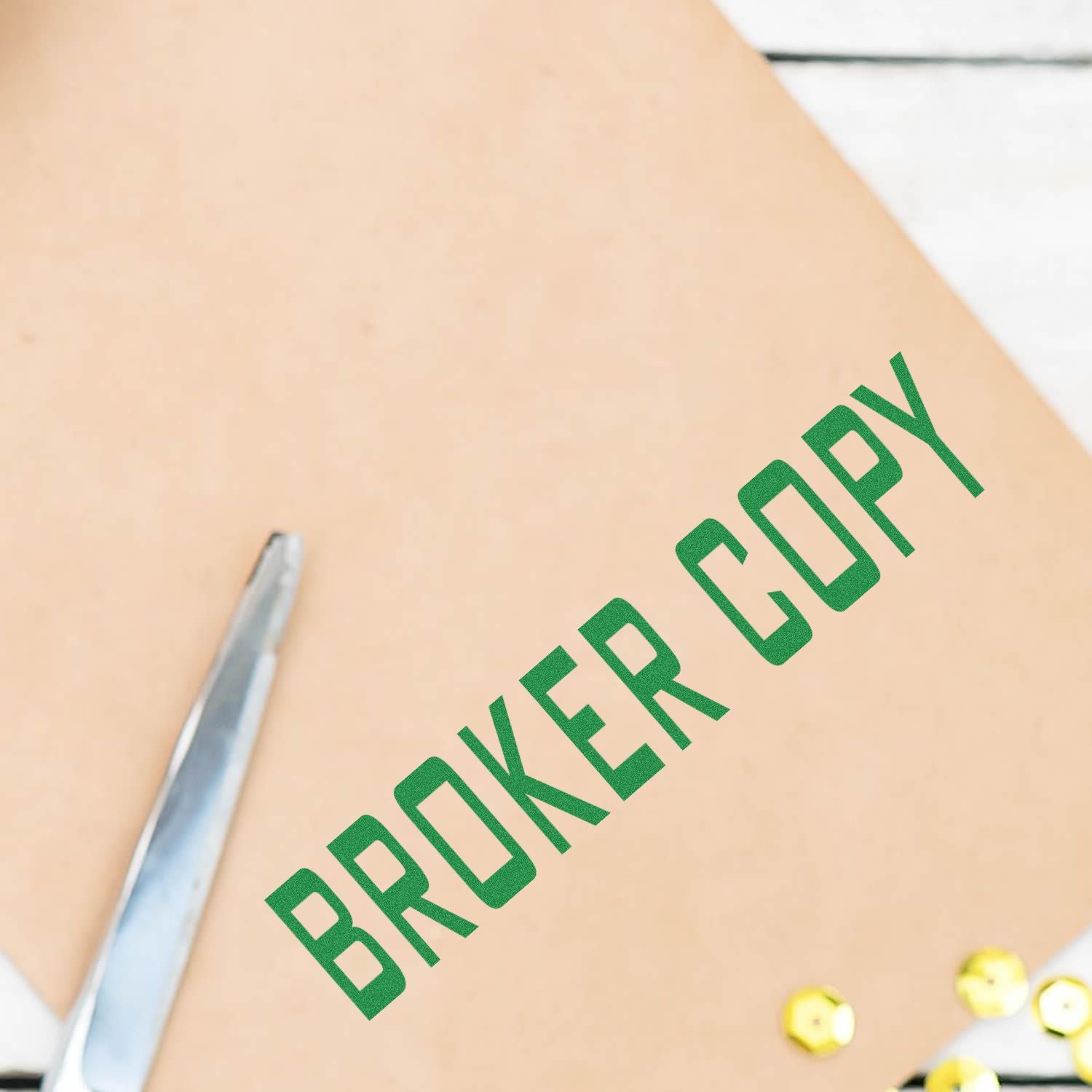 Large Pre-Inked Broker Copy Stamp in green ink on a brown envelope, with a silver pen and gold sequins nearby.