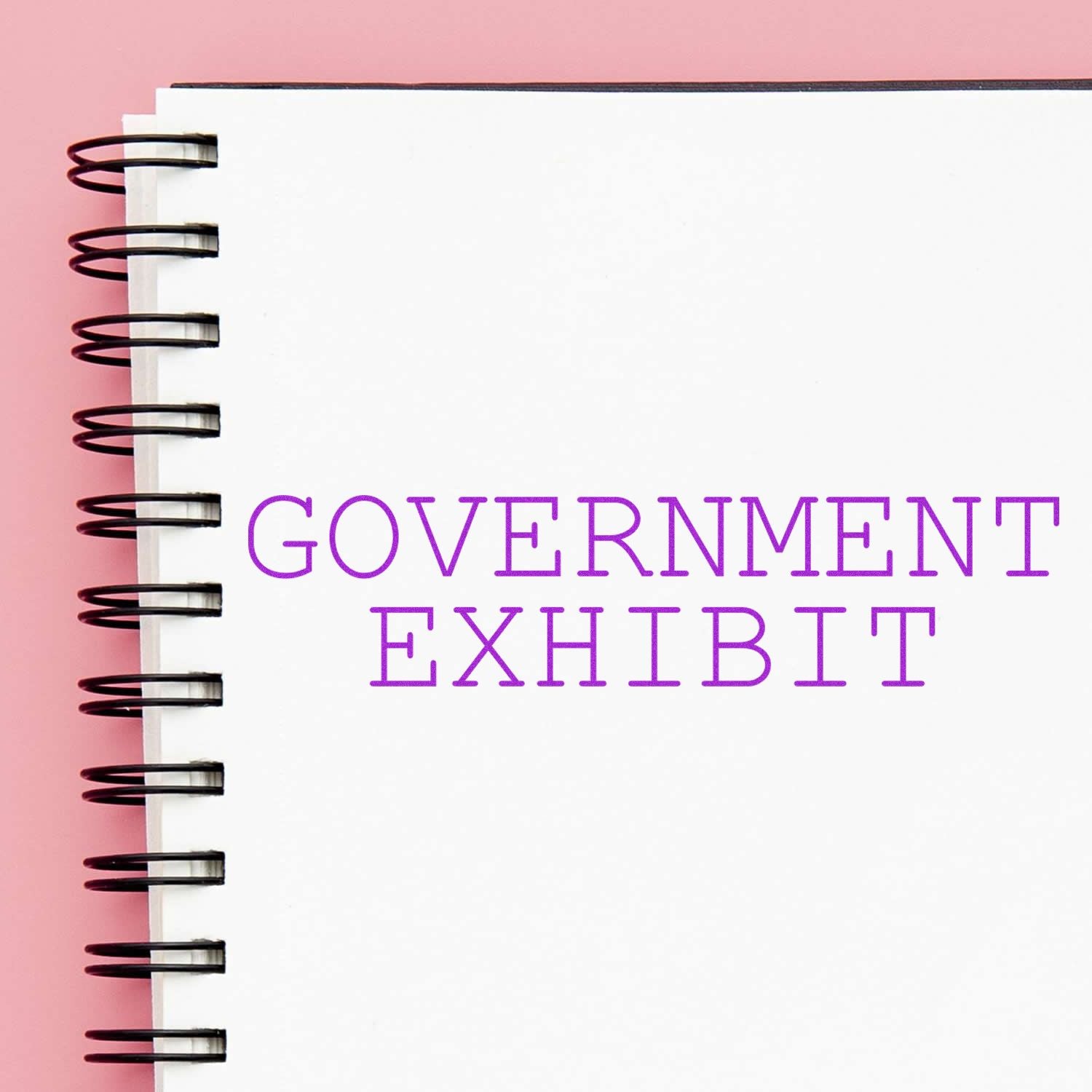 Large Pre-Inked Government Exhibit Stamp imprint on a white spiral notebook with a pink background.