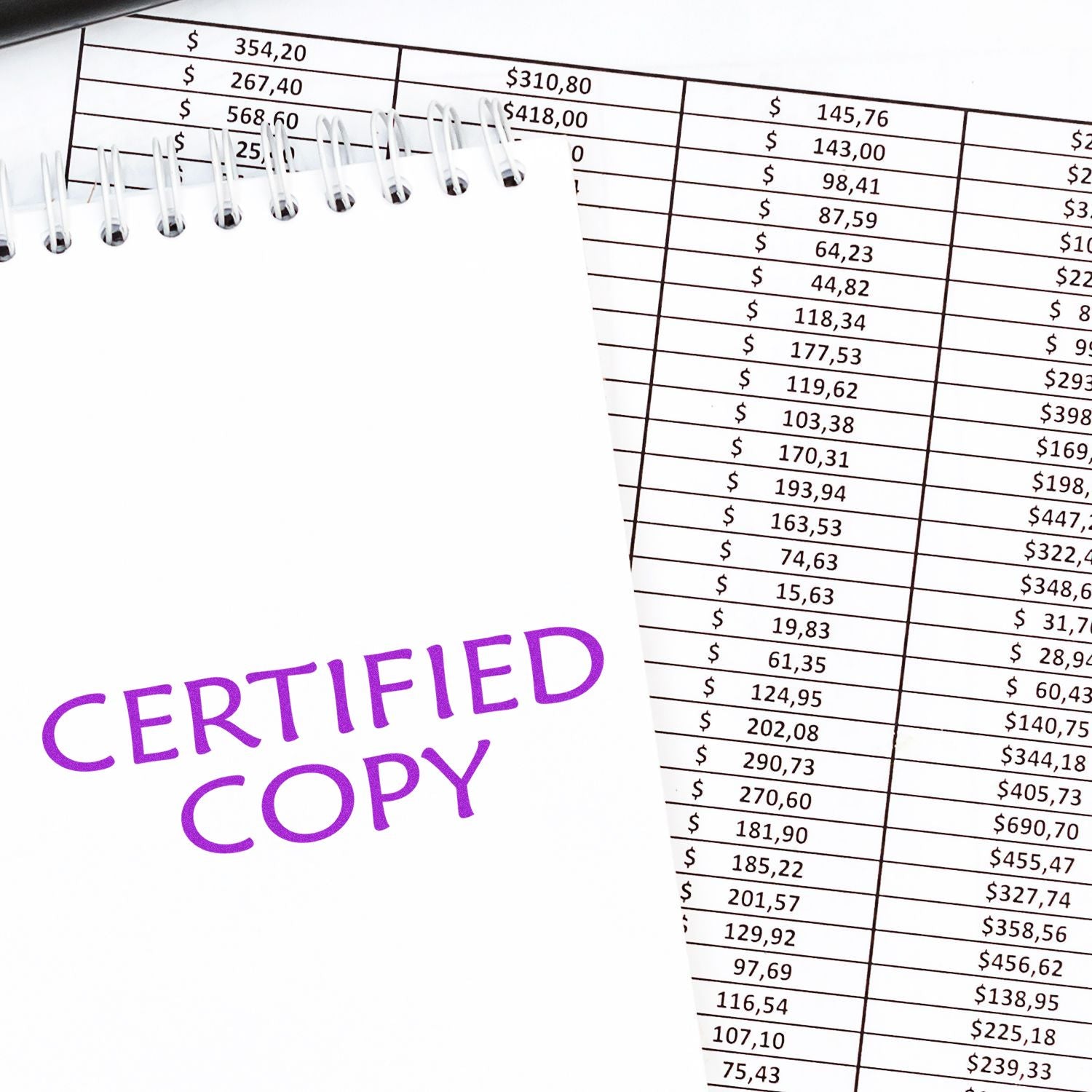 Large Pre-Inked Certified Copy Stamp in purple ink on a notepad, placed on top of financial documents with numbers and tables.