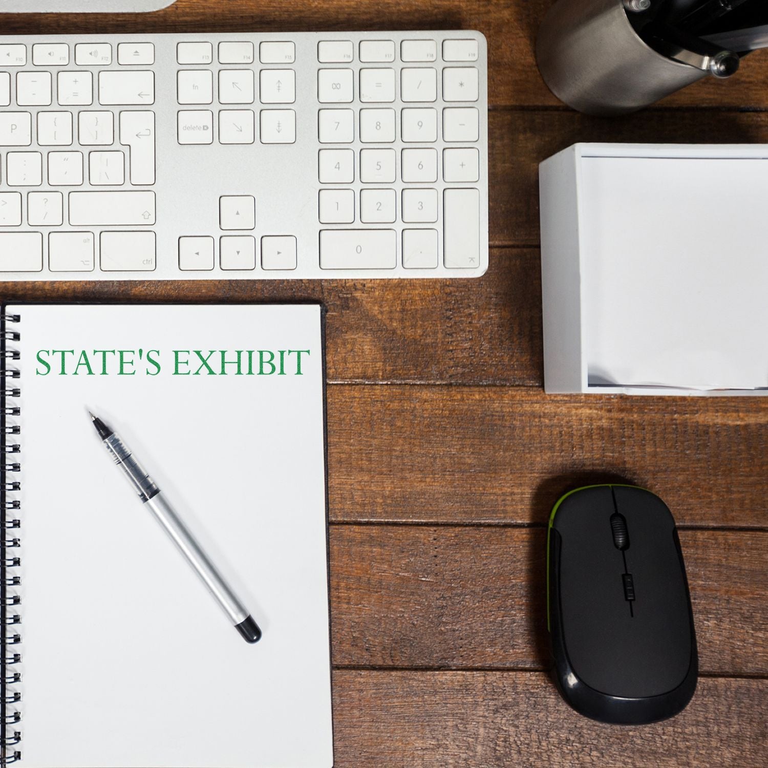 Large Pre-Inked States Exhibit Stamp on a wooden desk with a keyboard, mouse, pen, and notebook labeled STATE'S EXHIBIT.