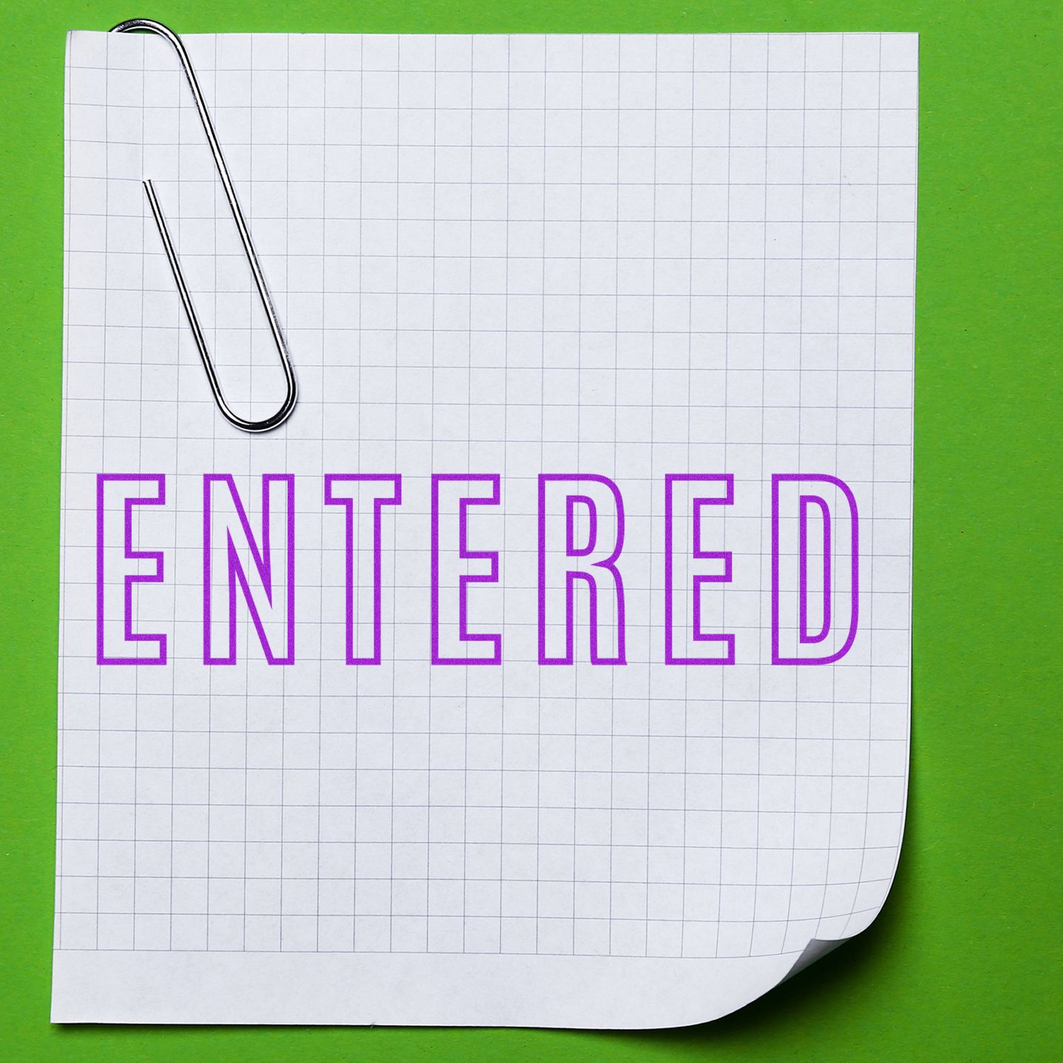 Large Pre-Inked Entered Outline Stamp in purple ink on a grid paper with a paperclip, placed on a green background.