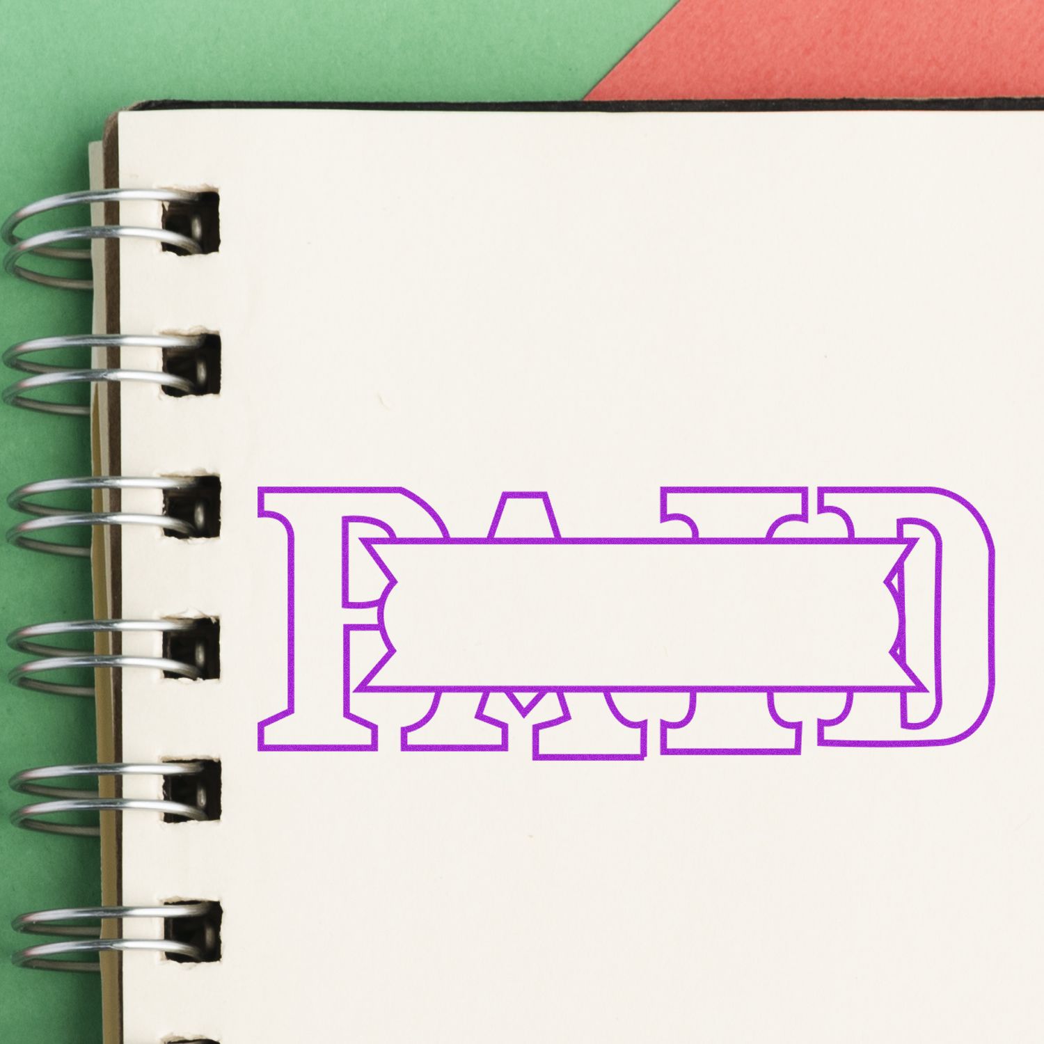 Large Pre-Inked Paid with Box Stamp imprint on a spiral notebook, showing the word PAID in purple with a blank banner in the center.