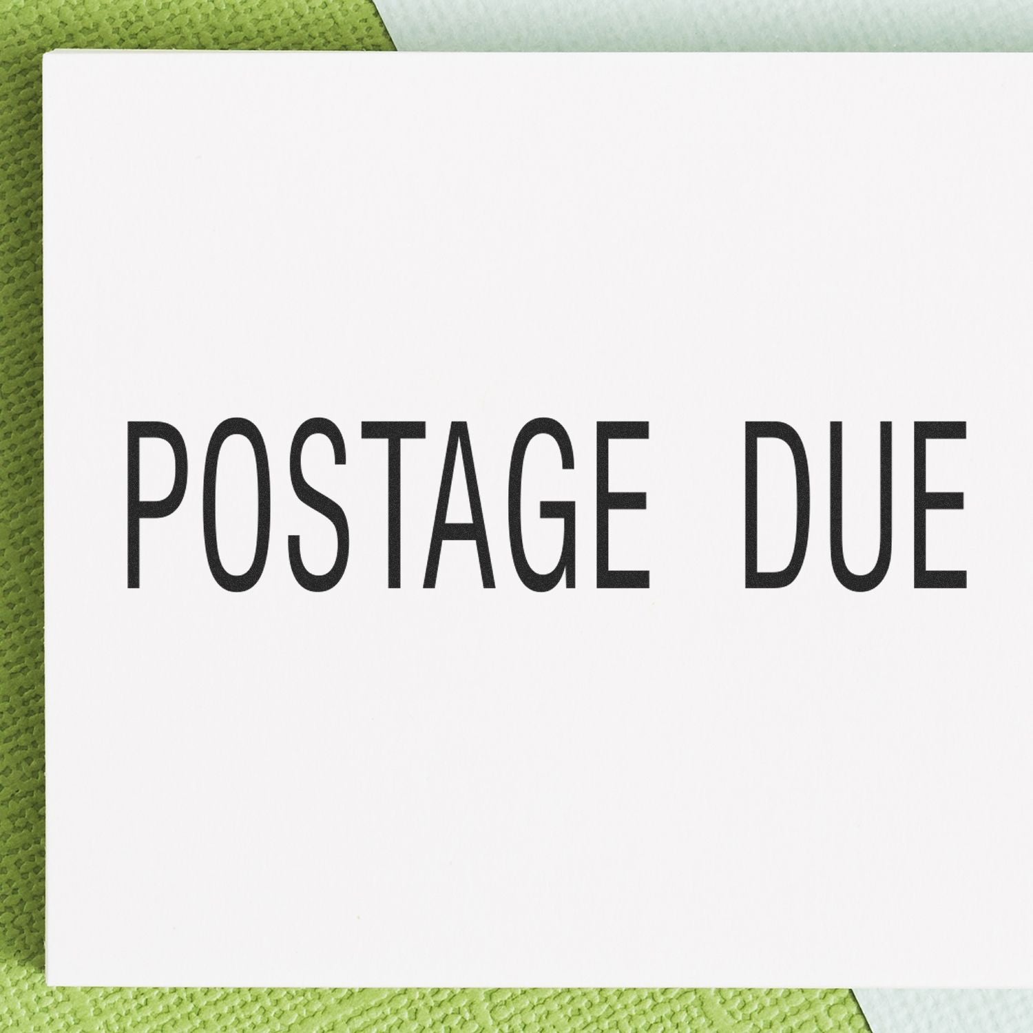 Large Pre-Inked Postage Due Stamp with bold black text on a white background, placed on a green textured surface.