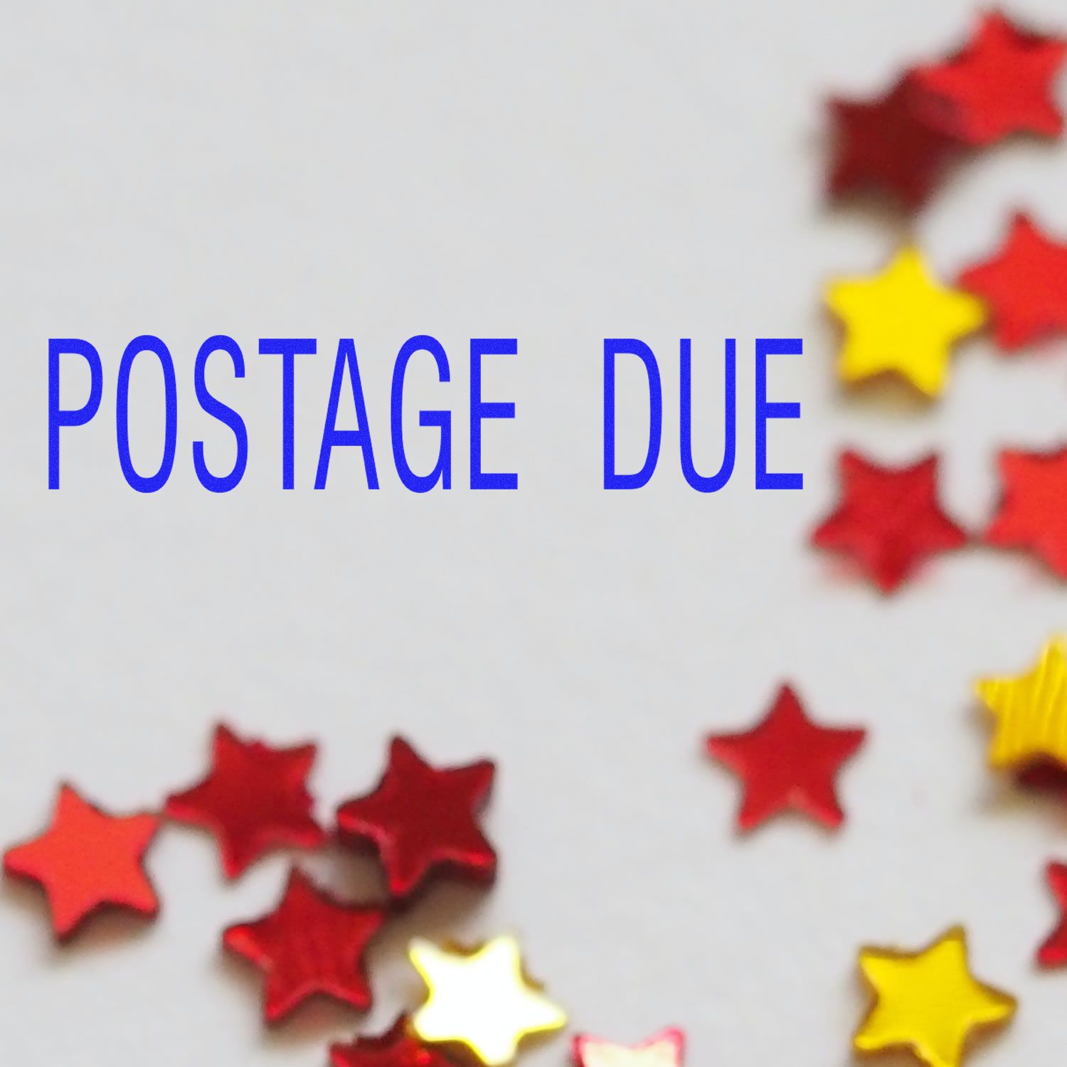 Large Pre-Inked Postage Due Stamp with blue text POSTAGE DUE on a white background, surrounded by red and yellow star-shaped confetti.