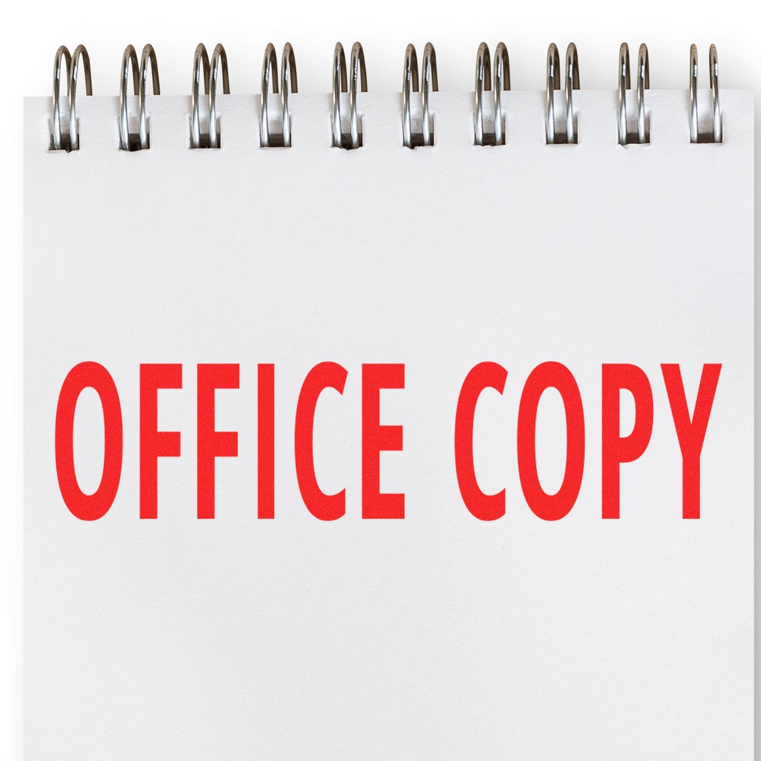 Large Pre-Inked Office Copy Stamp imprint in bold red letters on a white notepad with a spiral binding at the top.