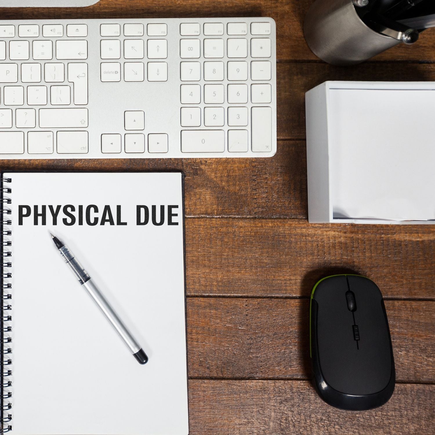 Large Pre-Inked Bold Physical Due Stamp on a notebook beside a keyboard, mouse, and pen on a wooden desk.