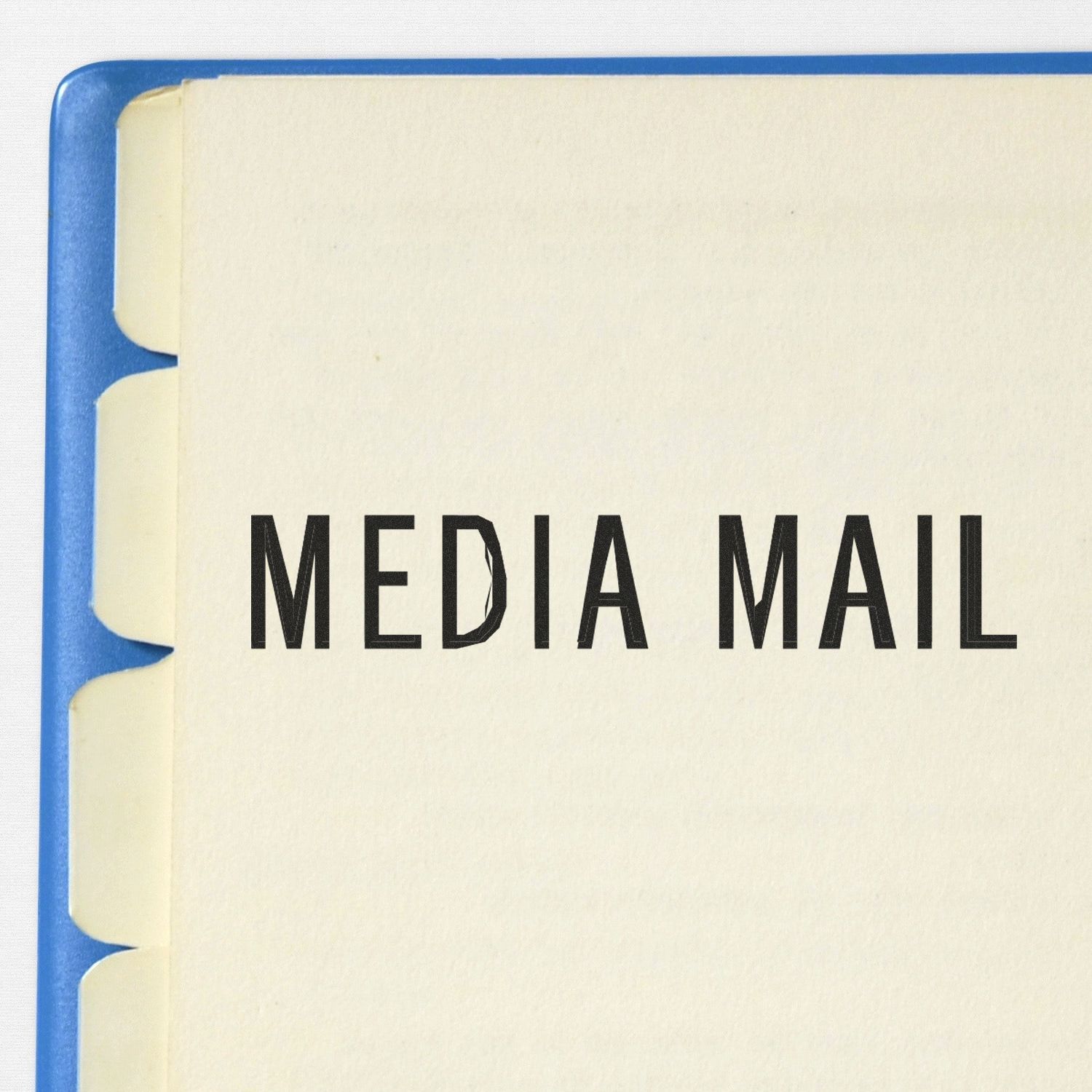 Large Pre-Inked Media Mail Stamp imprint on a beige paper with blue tabbed dividers visible on the left side.