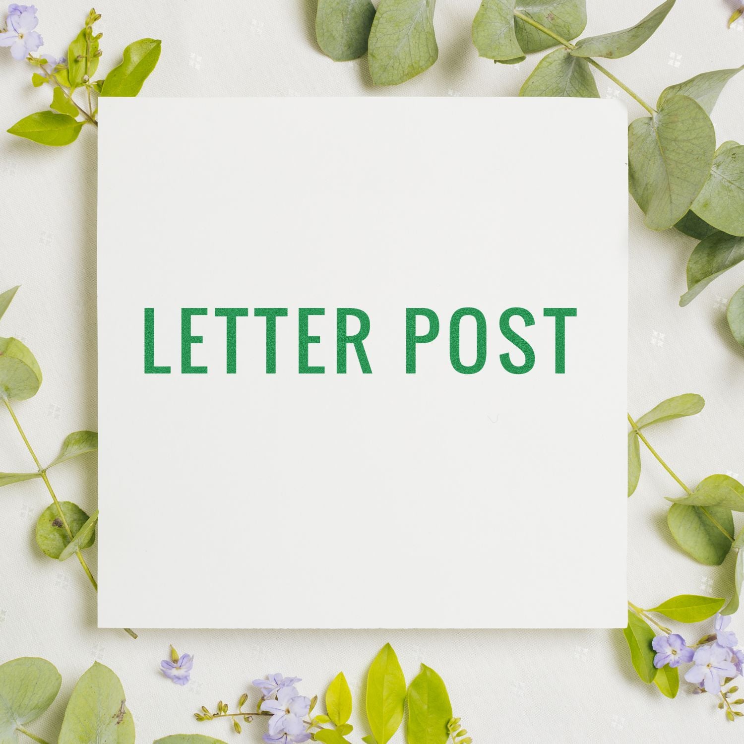 Large Pre-Inked Letter Post Stamp in green ink on white paper, surrounded by green leaves and small purple flowers.