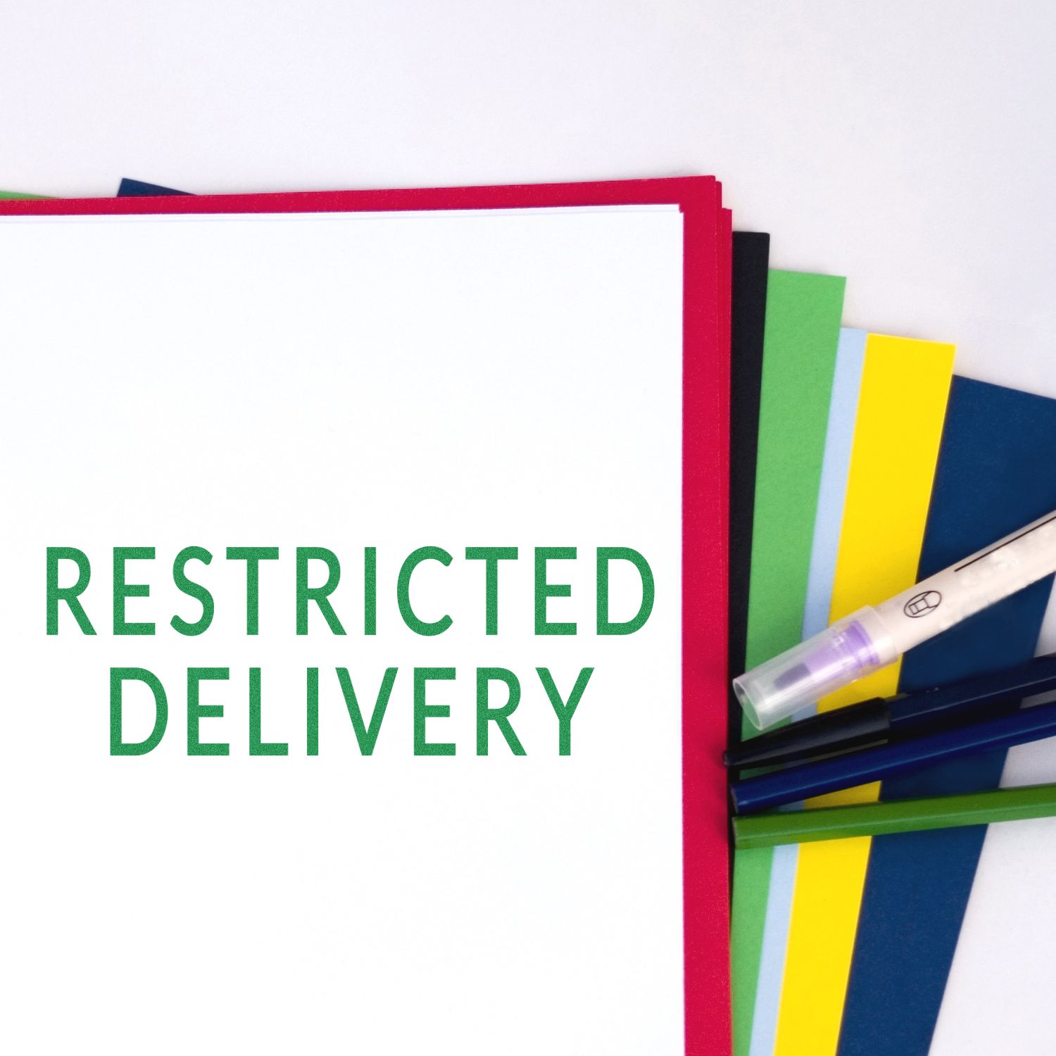 Large Pre-Inked Restricted Delivery Stamp in green ink on white paper, surrounded by colorful sheets and a pen.