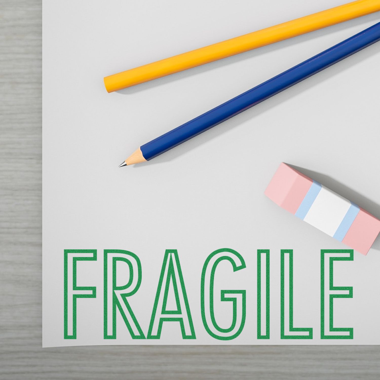 Large Pre-Inked Fragile Stamp on a white surface with two pencils and an eraser nearby.