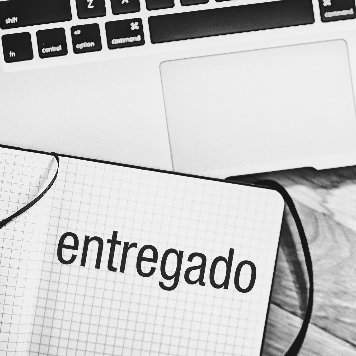 A Large Self Inking Entregado Stamp on a notebook with a laptop in the background.