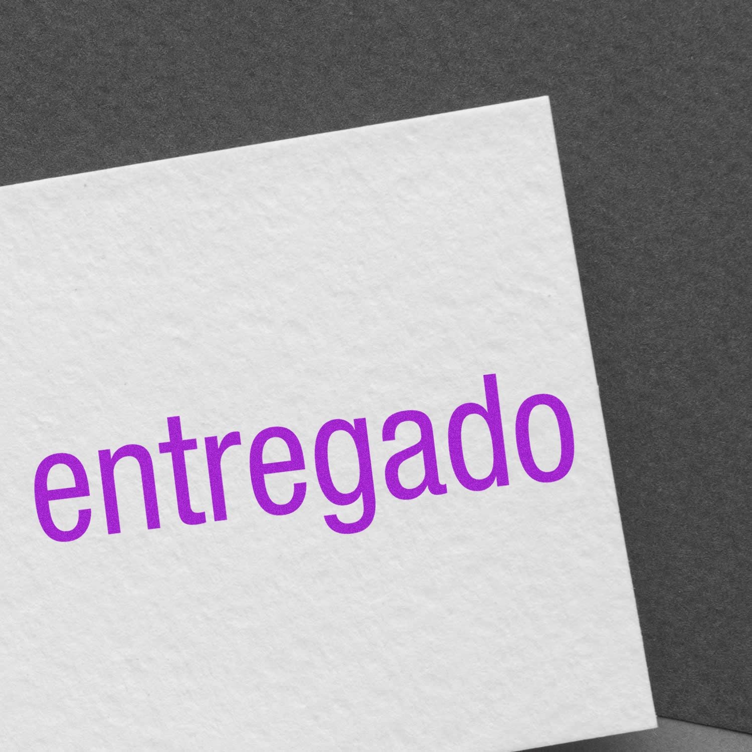 Large Self Inking Entregado Stamp imprint in purple ink on white textured paper, placed on a dark gray background.