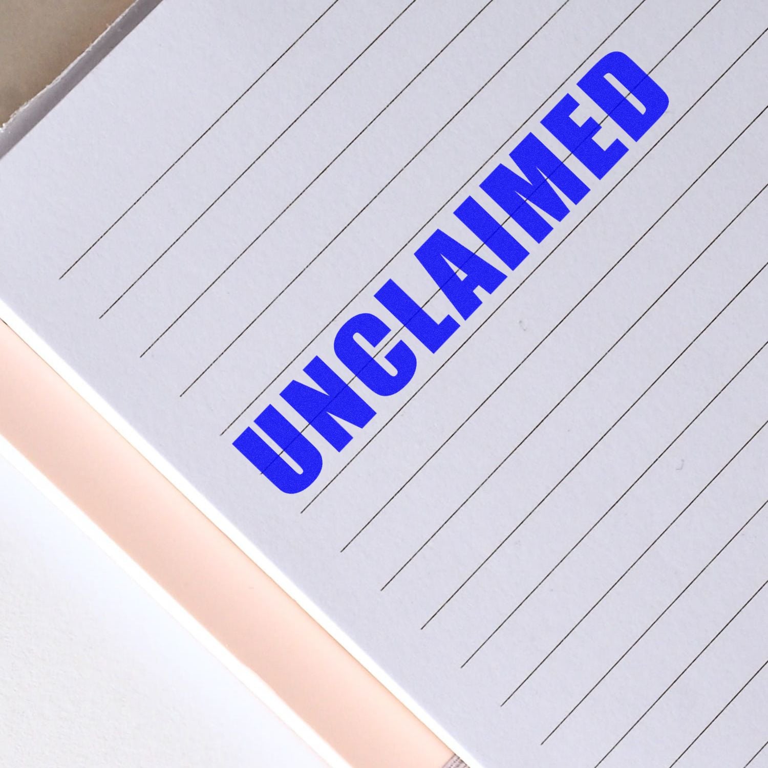 Large Pre-Inked Unclaimed Stamp in blue ink on a lined notebook page, indicating unclaimed status.